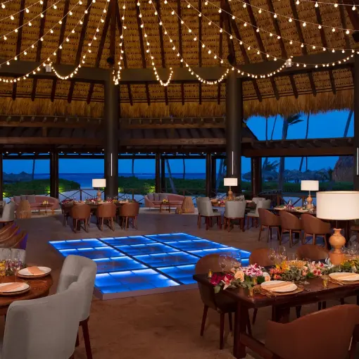 Palapa wedding reception with a blue illuminated dance floor at Secrets Royal Beach, Punta Cana