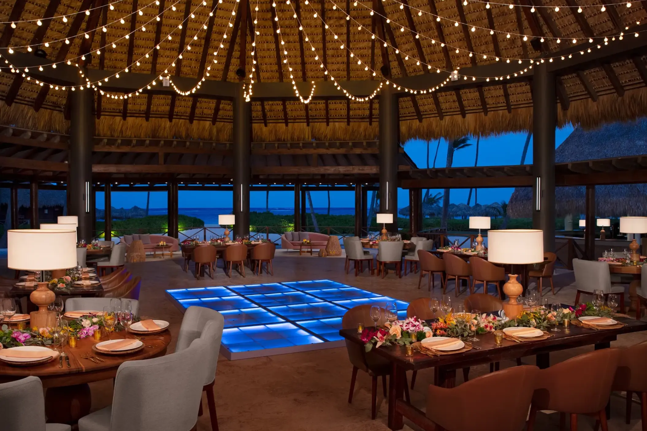 Palapa wedding reception with a blue illuminated dance floor at Secrets Royal Beach, Punta Cana