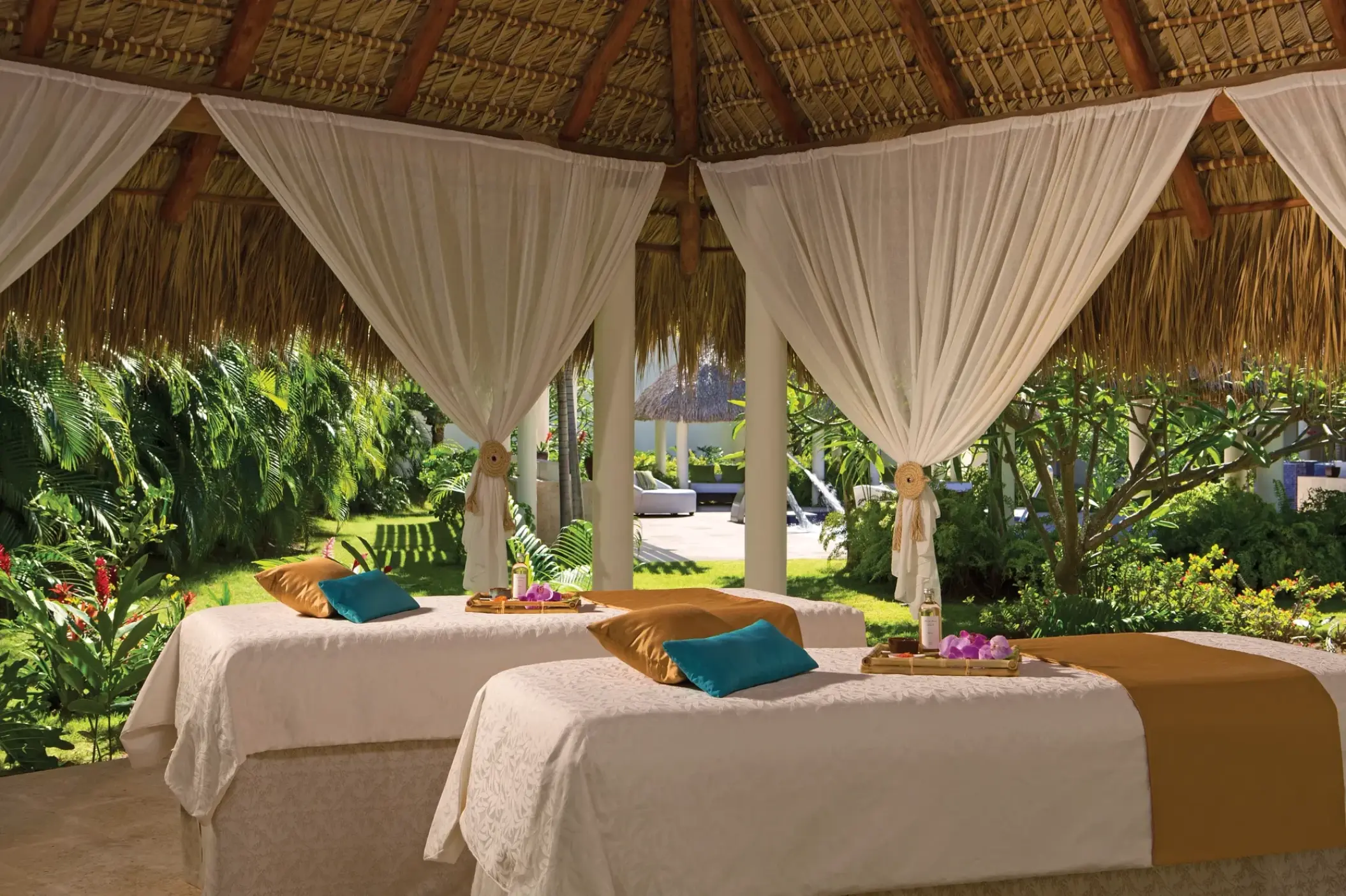 Outdoor spa treatment beds under a thatched roof palapa at Secrets Royal Beach, Punta Cana