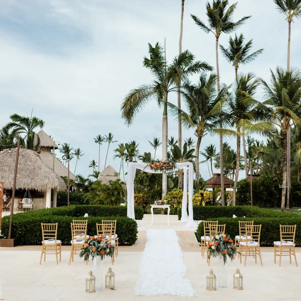 Outdoor wedding ceremony setup with white floral arch and gold chairs at Secrets Royal Beach, Punta Cana