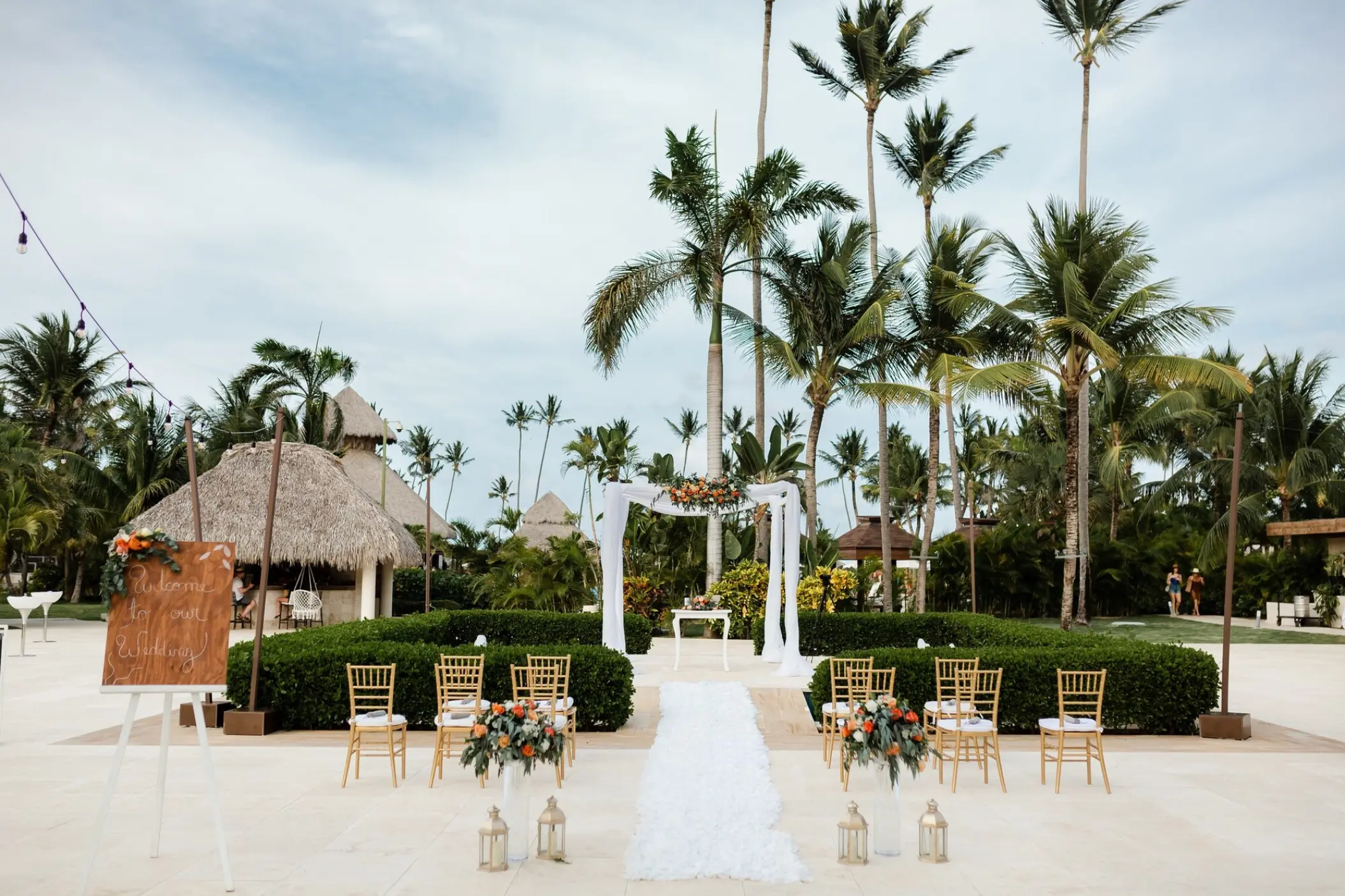 Outdoor wedding ceremony setup with white floral arch and gold chairs at Secrets Royal Beach, Punta Cana