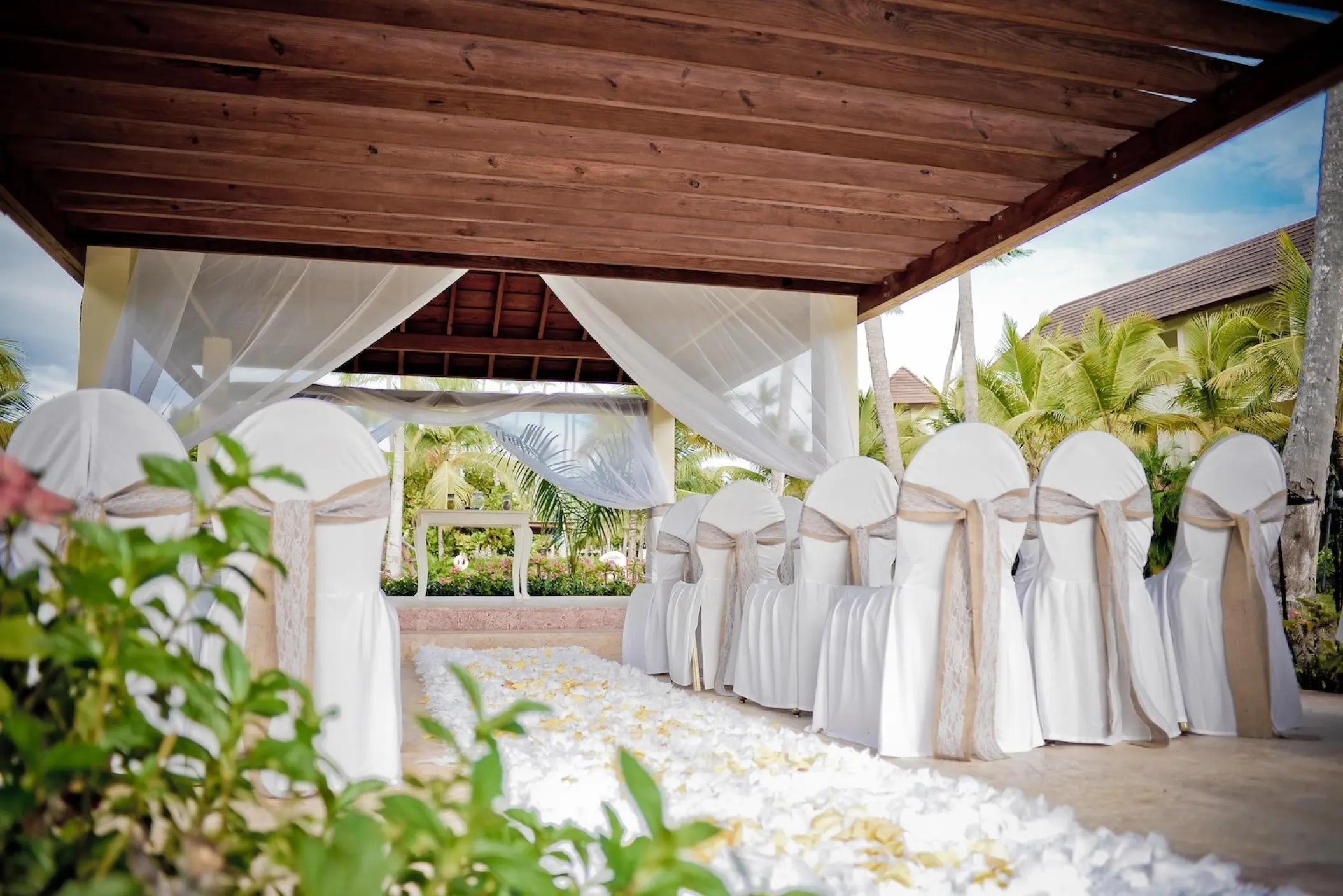 Garden wedding ceremony setup under a wooden pergola at Secrets Royal Beach, Punta Cana