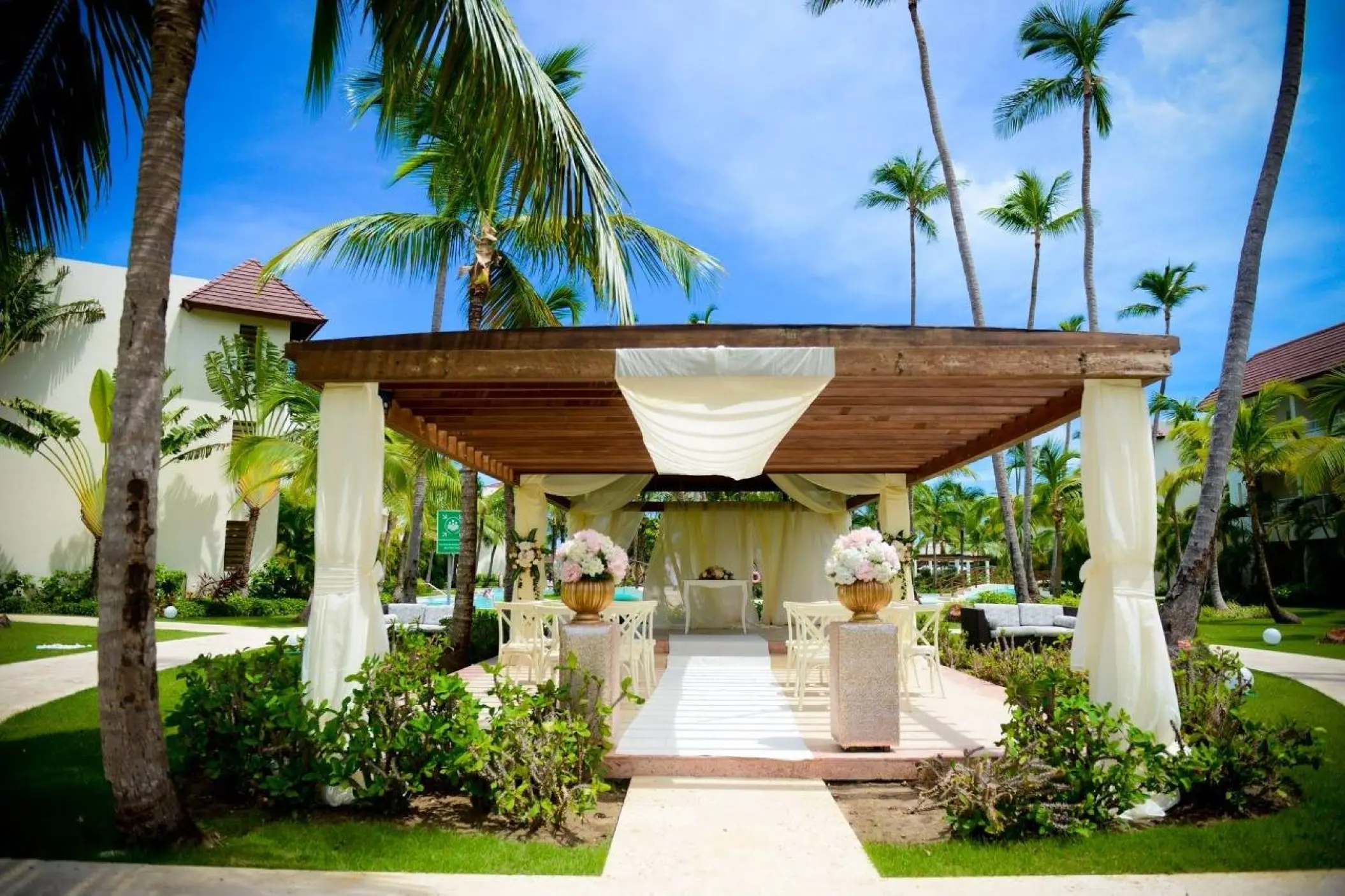 Tropical garden wedding ceremony under a wooden pergola at Secrets Royal Beach, Punta Cana
