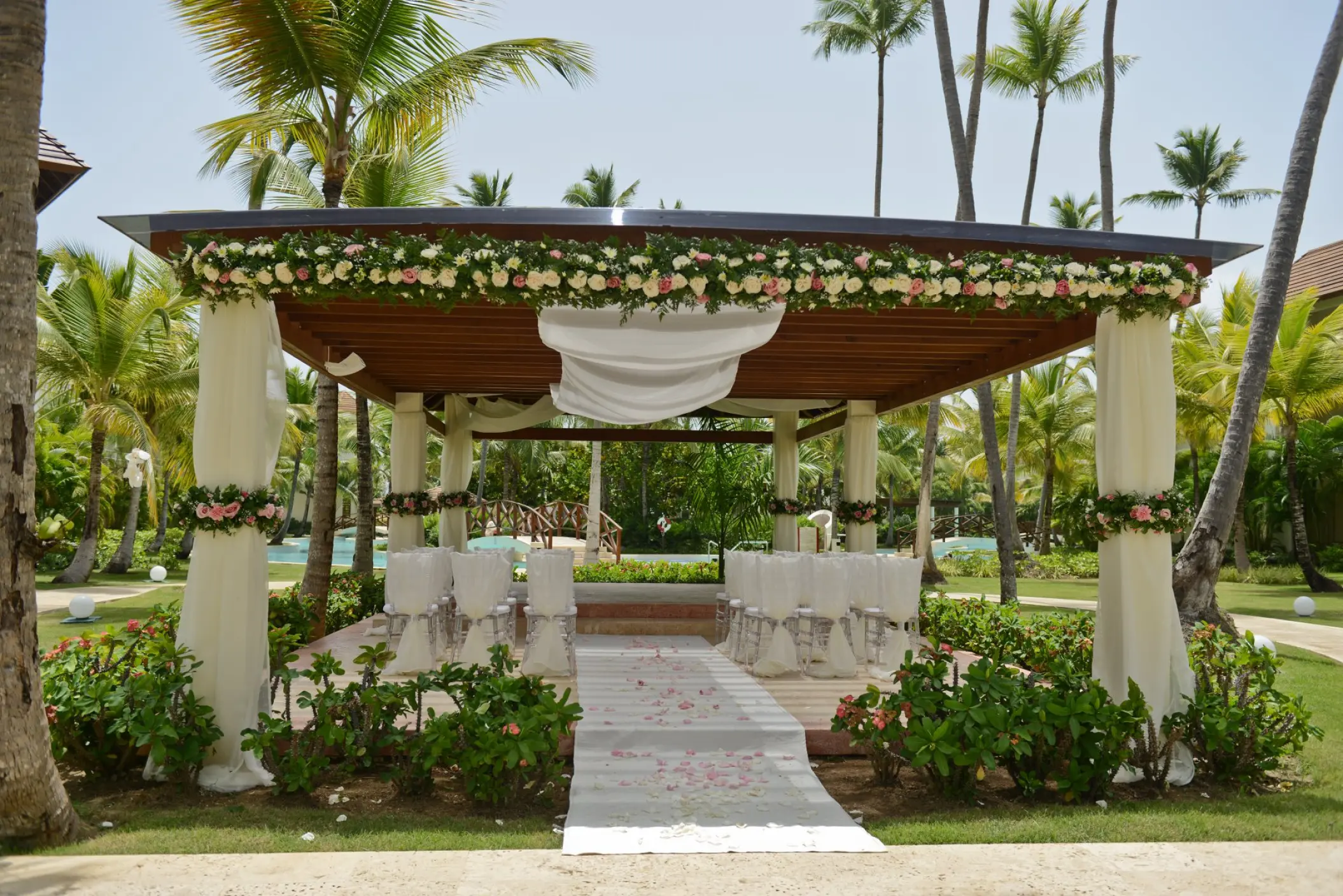 Garden wedding ceremony setup under a floral gazebo at Secrets Royal Beach, Punta Cana