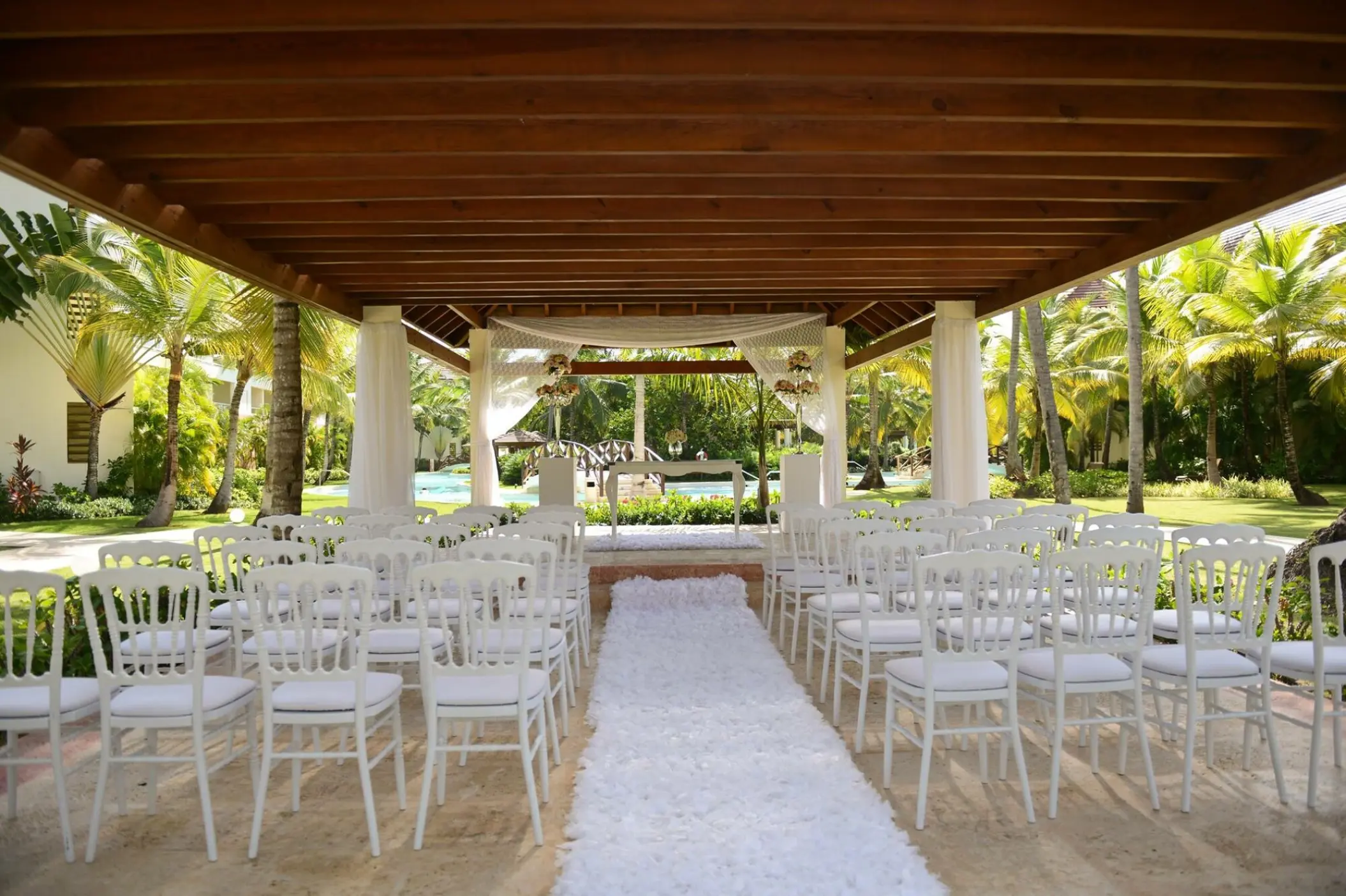 Tropical garden wedding ceremony under a wooden gazebo at Secrets Royal Beach, Punta Cana