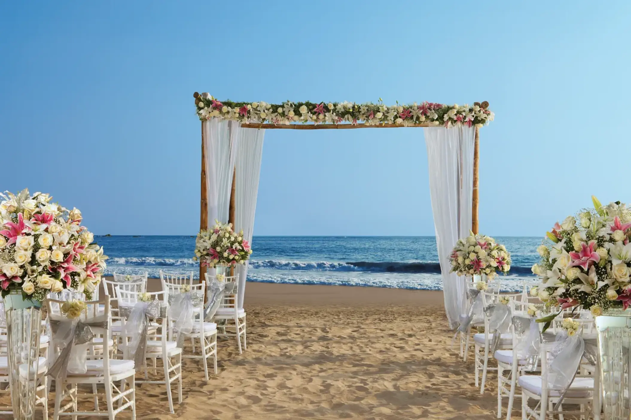 Beachfront wedding ceremony with a floral wooden arch at Secrets Vallarta Bay, Puerto Vallarta