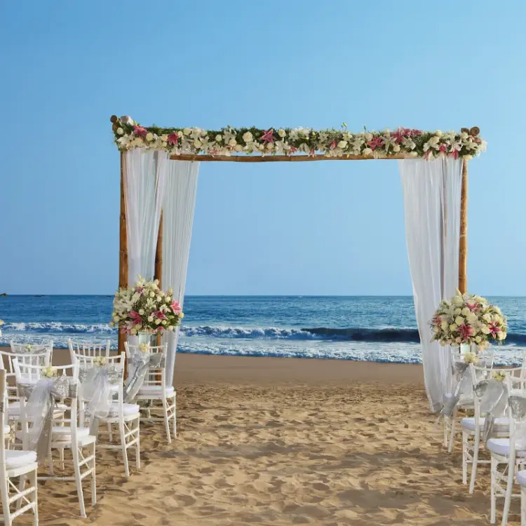 Beachfront wedding ceremony with a floral wooden arch at Secrets Vallarta Bay, Puerto Vallarta