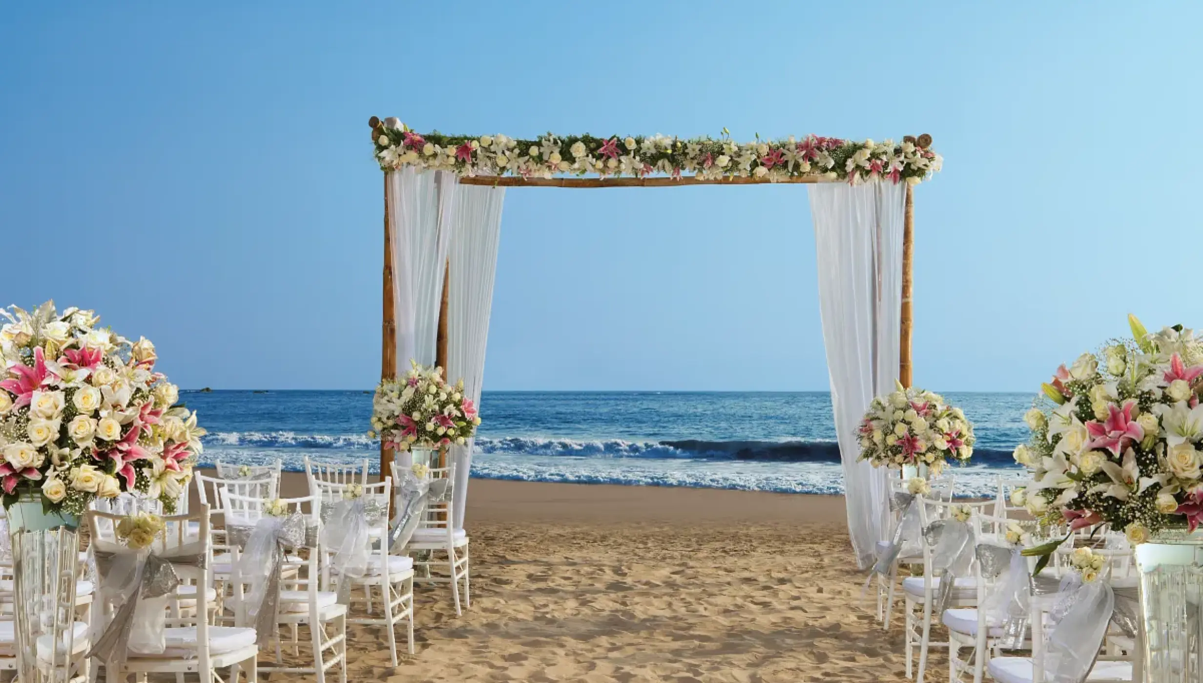 Beachfront wedding ceremony with a floral wooden arch at Secrets Vallarta Bay, Puerto Vallarta