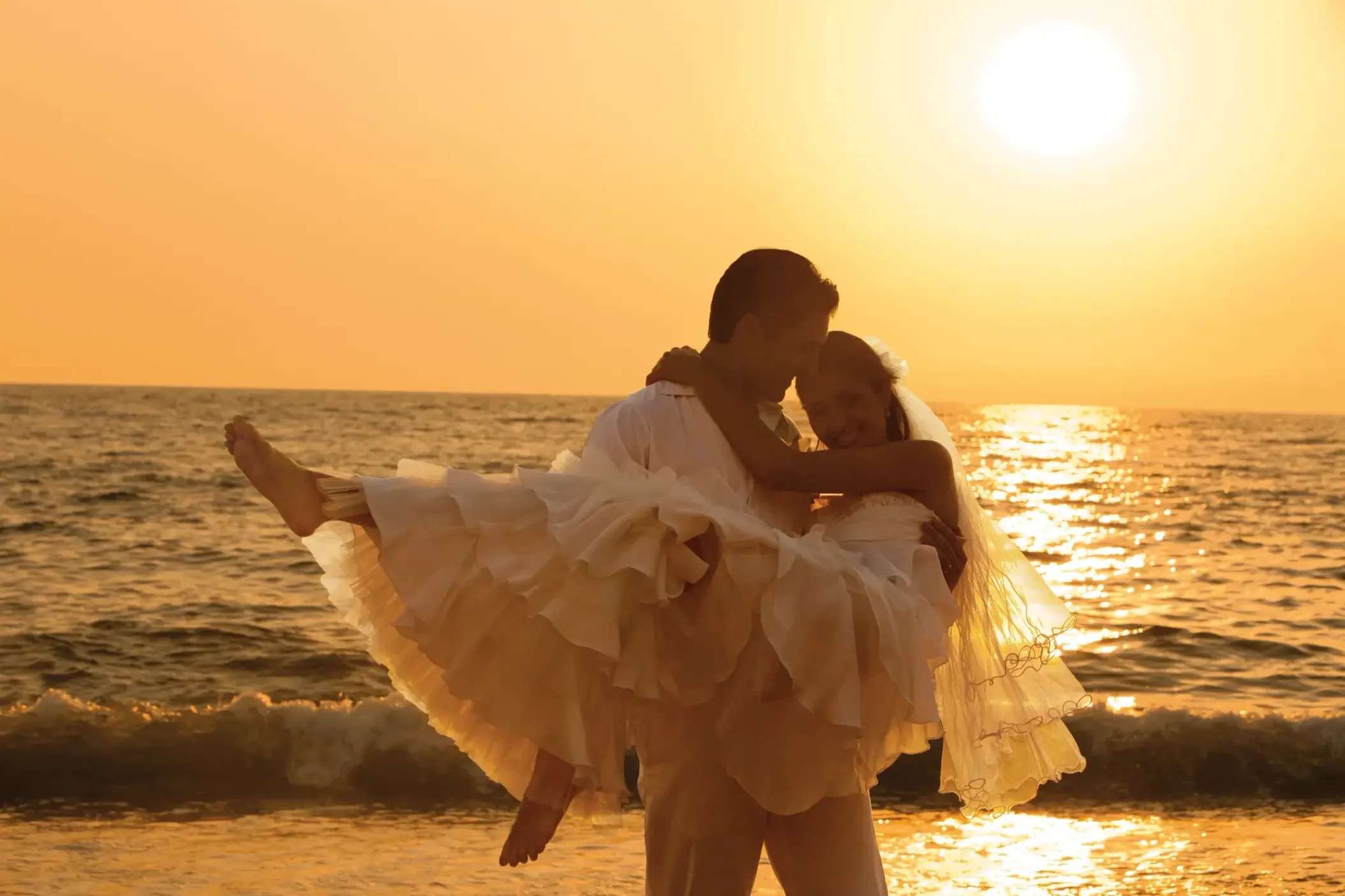 Groom carrying bride on the beach at sunset during a wedding at Secrets Vallarta Bay, Puerto Vallarta