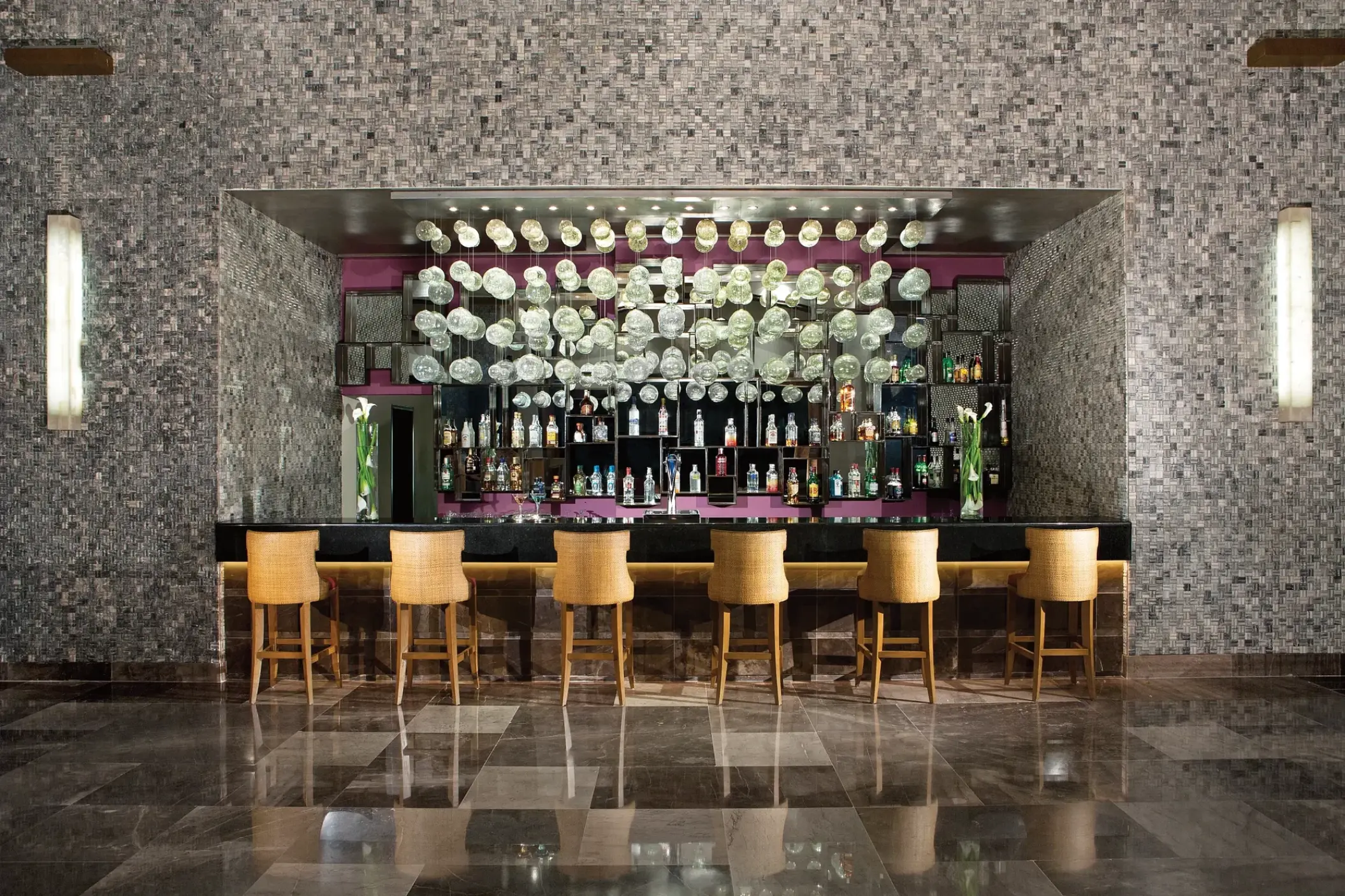 Modern lobby bar with mosaic walls and hanging glass ornaments at Secrets Vallarta Bay, Puerto Vallarta