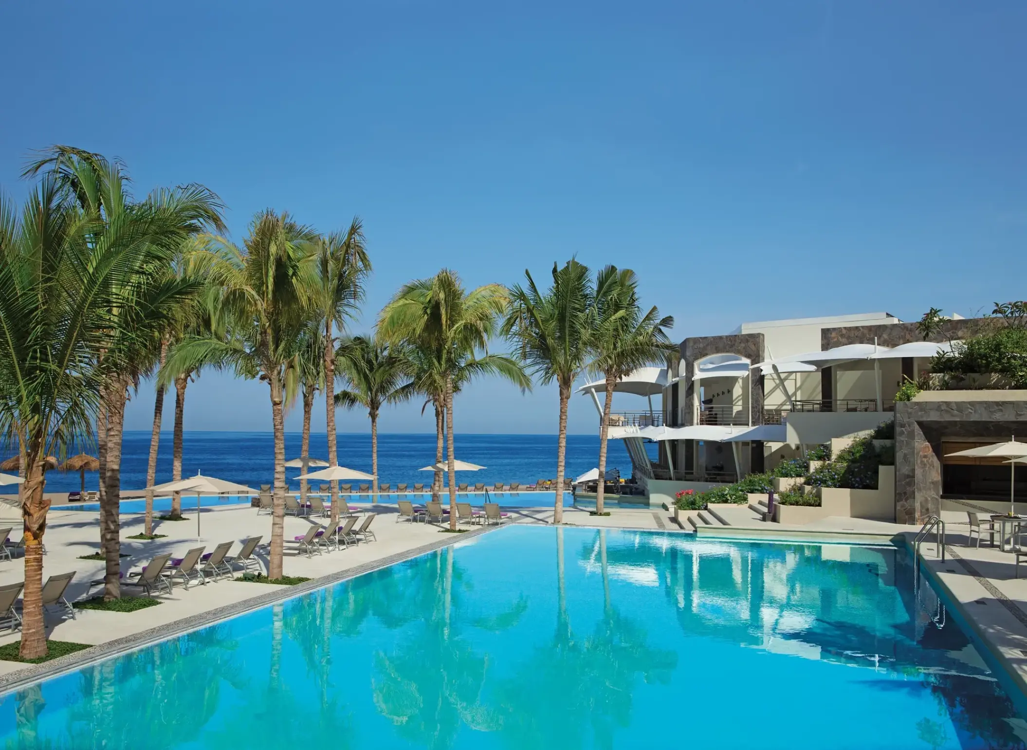 Secrets Vallarta Bay main pool and palm trees overlooking the ocean, Puerto Vallarta