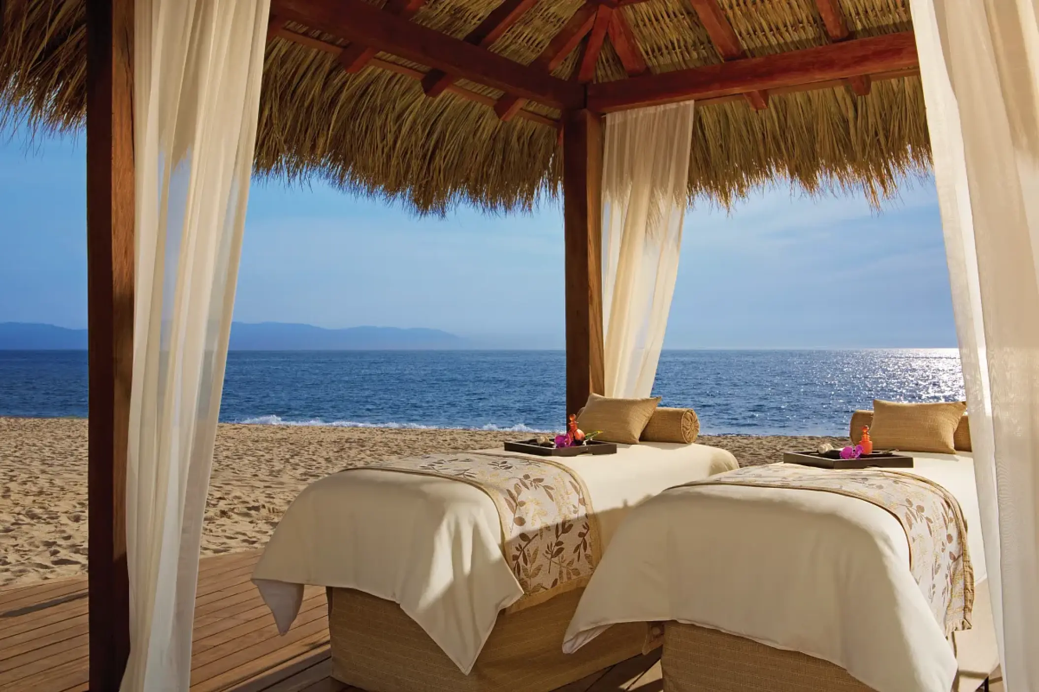 Beachfront spa massage tables under a thatched palapa at Secrets Vallarta Bay, Puerto Vallarta