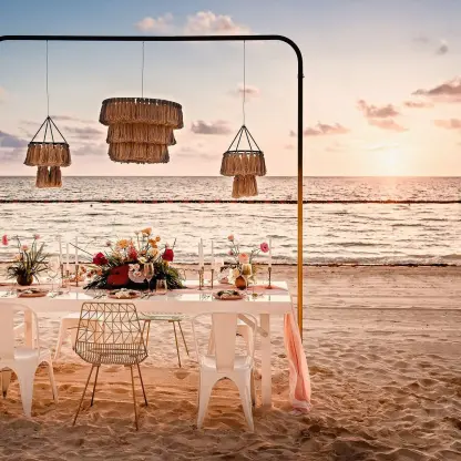 Beachfront wedding reception setup with hanging lanterns at Sensira Riviera Maya at sunset