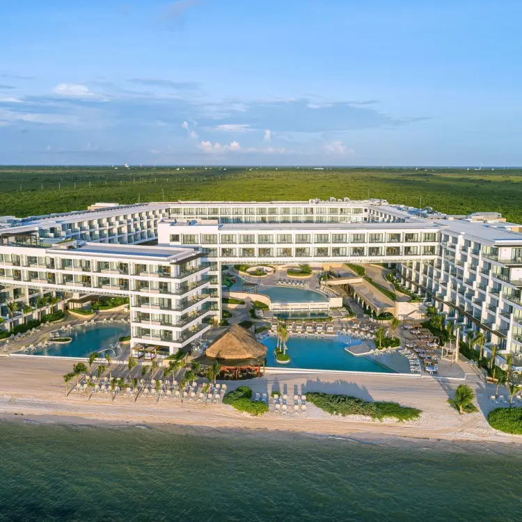 Aerial view of Sensira Riviera Maya beachfront buildings and pools surrounded by lush greenery