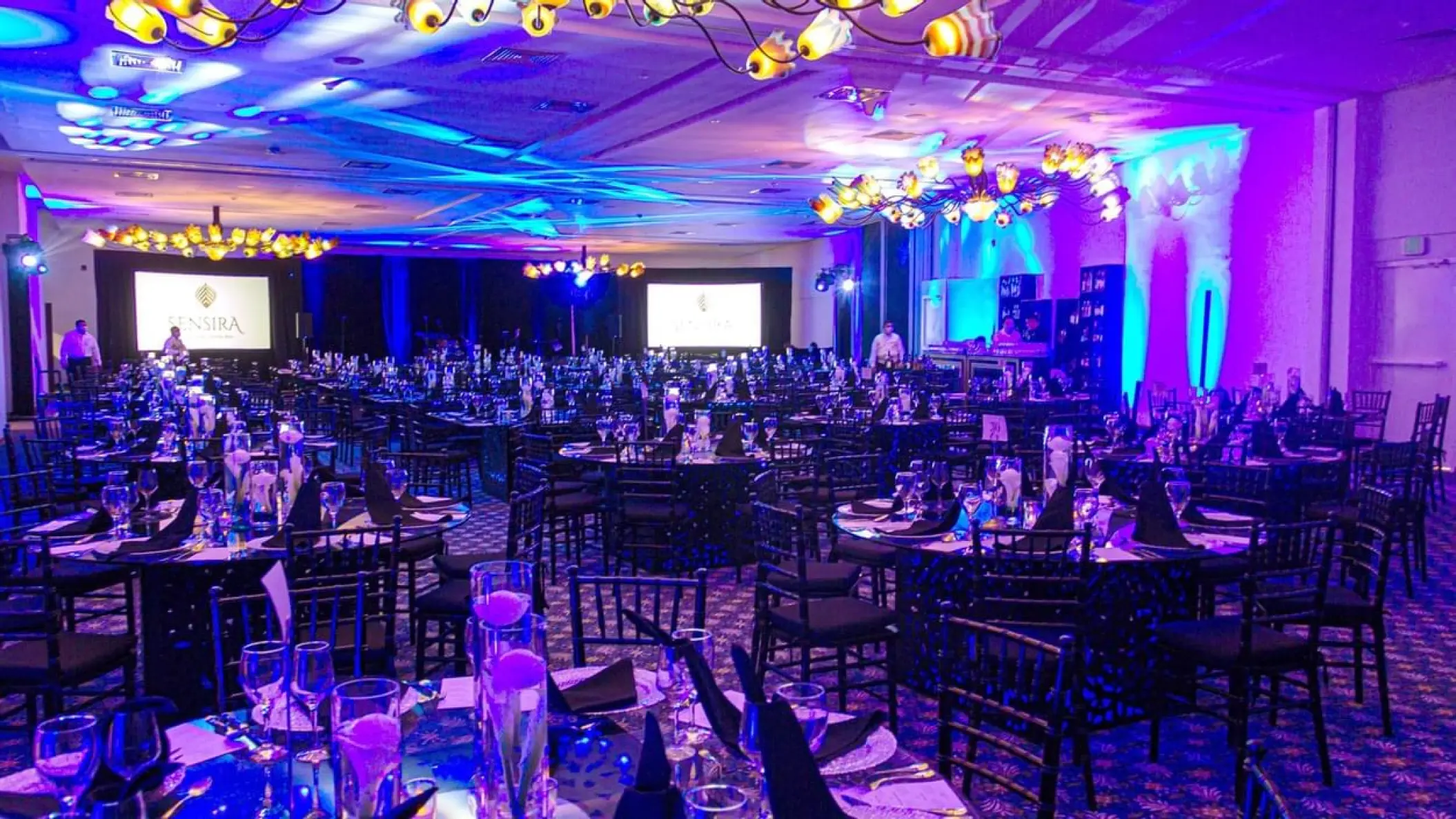 Indoor wedding reception with purple lighting and round tables at Sensira Resort, Riviera Maya