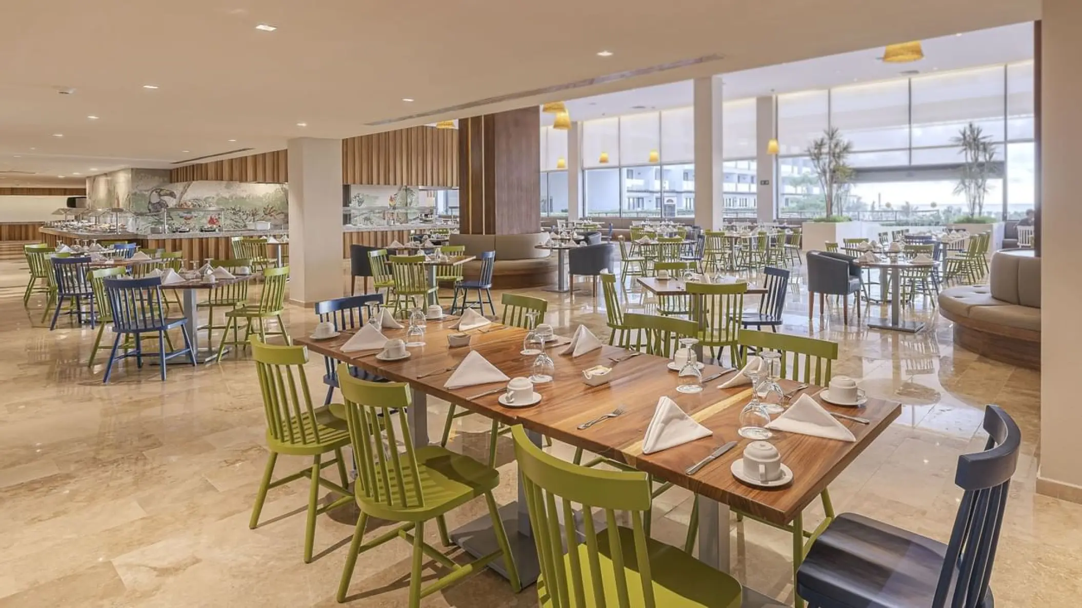 La Pergola restaurant with wooden tables and green chairs at Sensira Riviera Maya