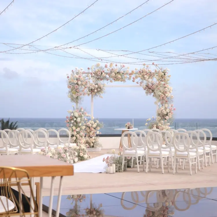 Oceanview terrace wedding ceremony with floral arch and white chairs at Sensira Riviera Maya