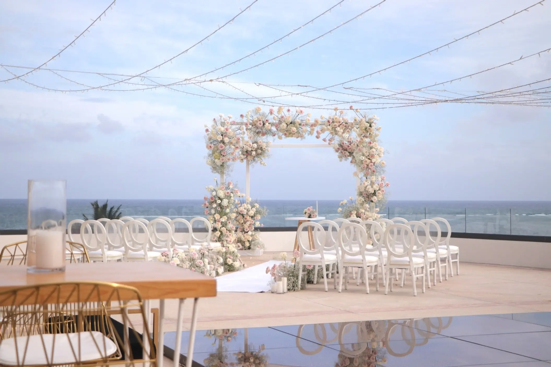 Oceanview terrace wedding ceremony with floral arch and white chairs at Sensira Riviera Maya