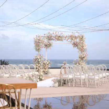Oceanview terrace wedding ceremony with floral arch and white chairs at Sensira Riviera Maya