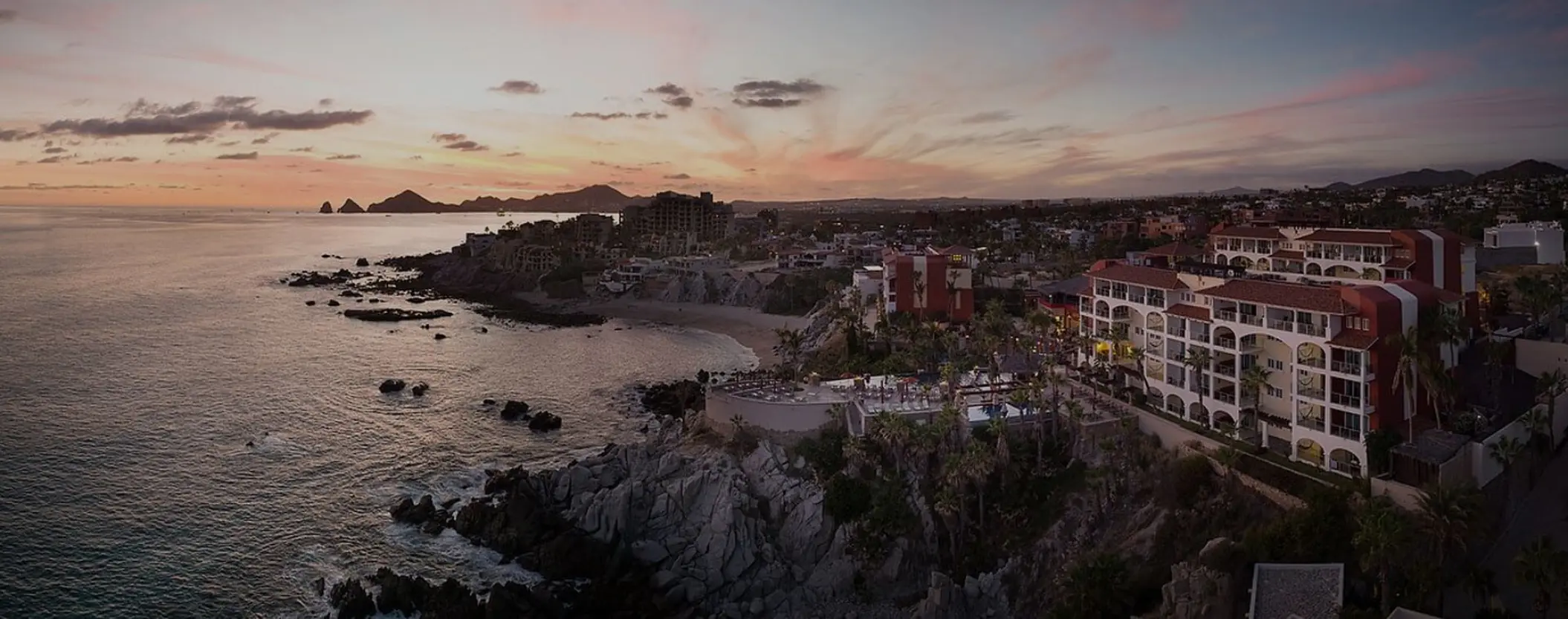 Aerial view of Hyatt Vacation Club at Sirena del Mar buildings on a rocky clifftop at sunset, Cabo San Lucas