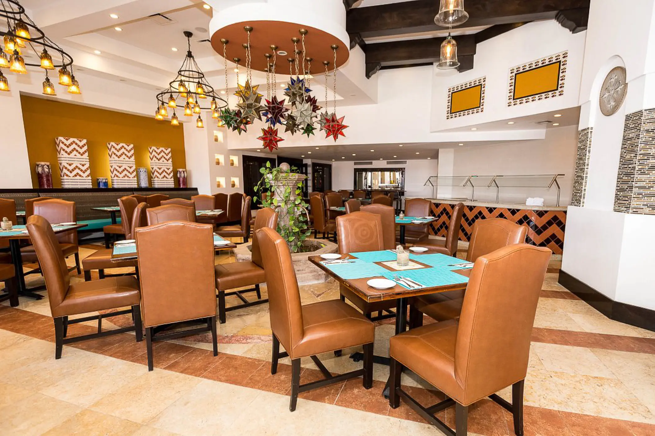 Indoor restaurant dining area with leather chairs and colorful pendant lights at Hyatt Vacation Club at Sirena del Mar
