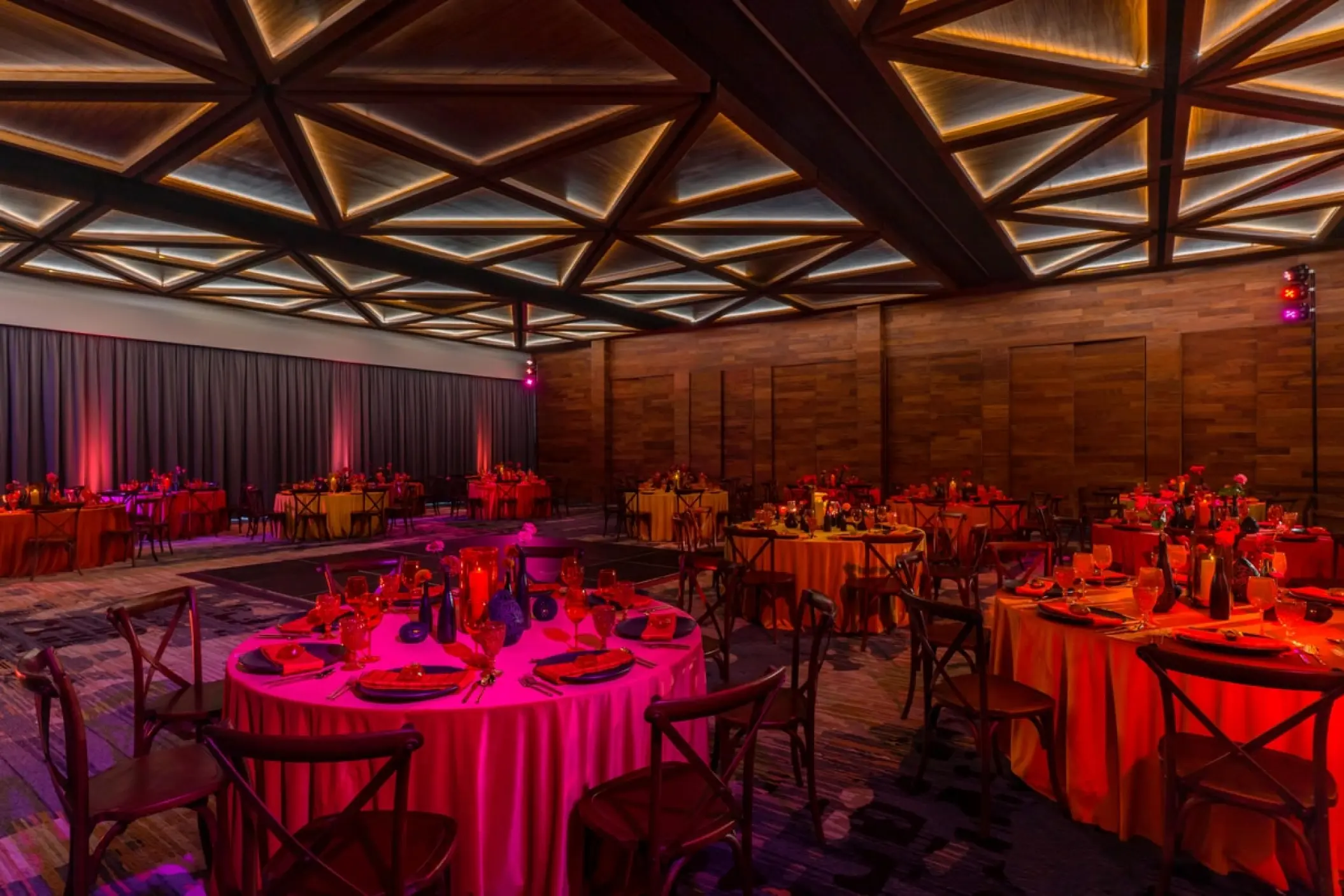 Indoor wedding reception with round tables and geometric ceiling at Solaz Los Cabos, Cabo San Lucas