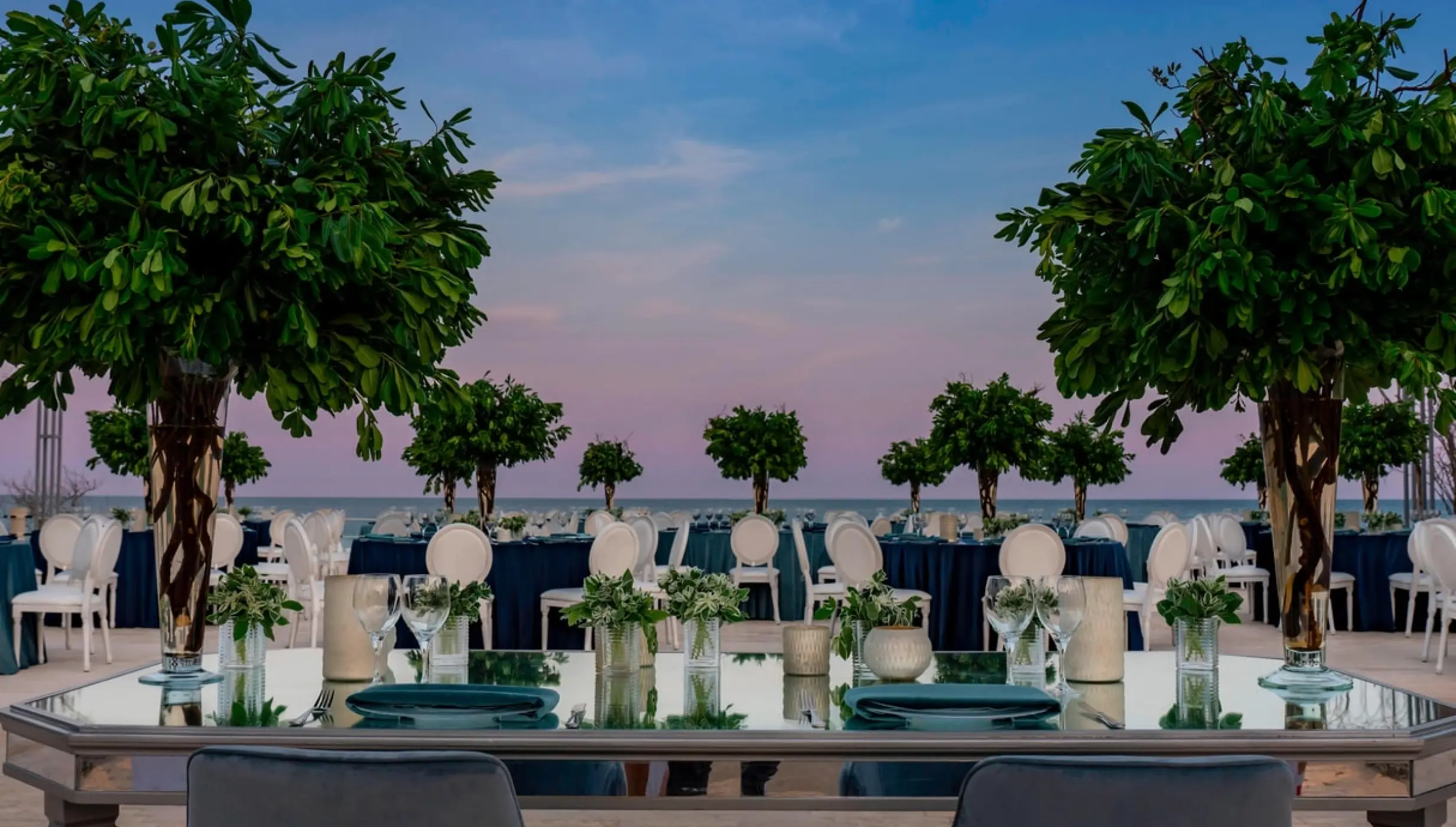Outdoor wedding reception with mirrored tables and tall greenery at Solaz Los Cabos, Cabo San Lucas