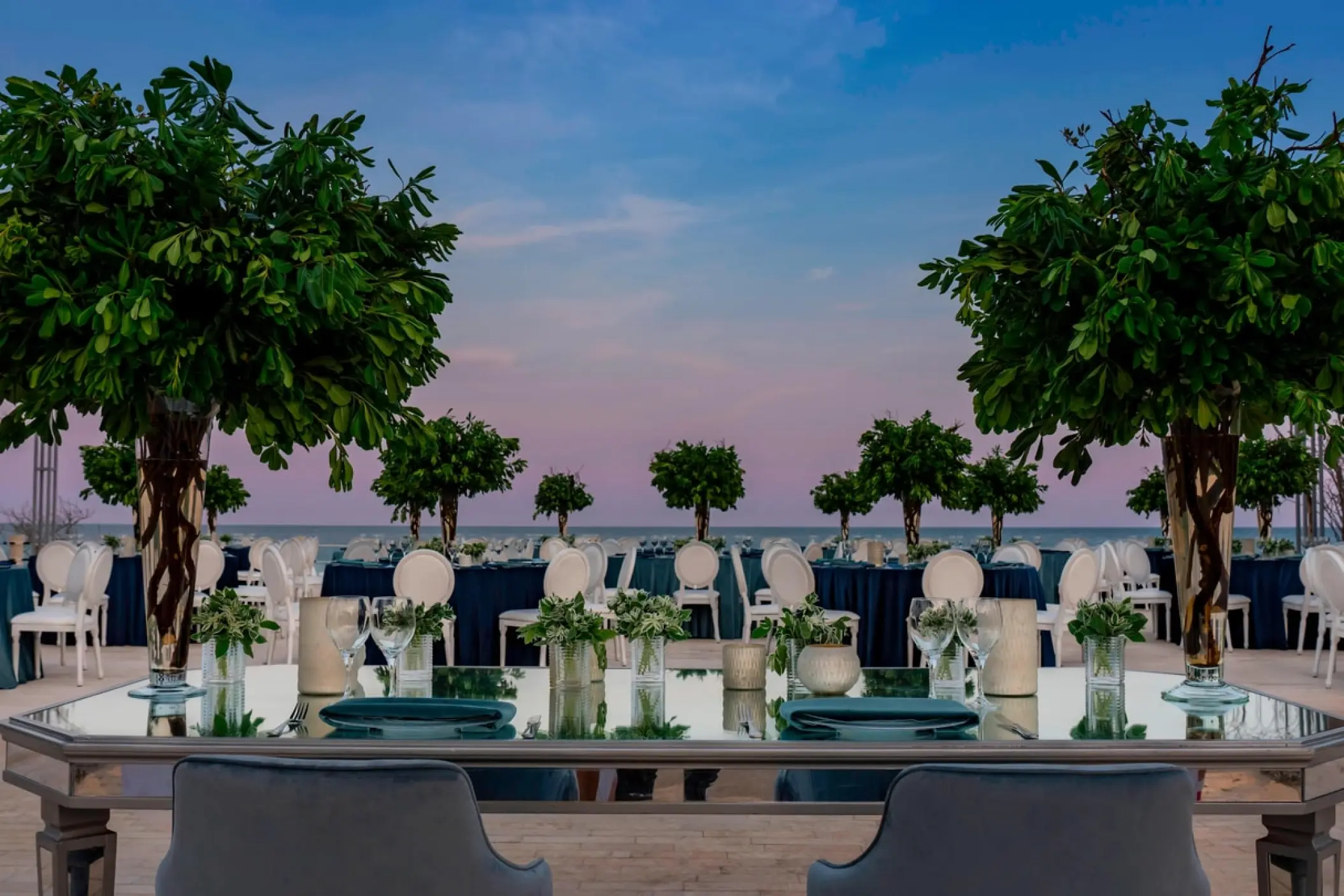 Outdoor wedding reception with mirrored tables and tall greenery at Solaz Los Cabos, Cabo San Lucas