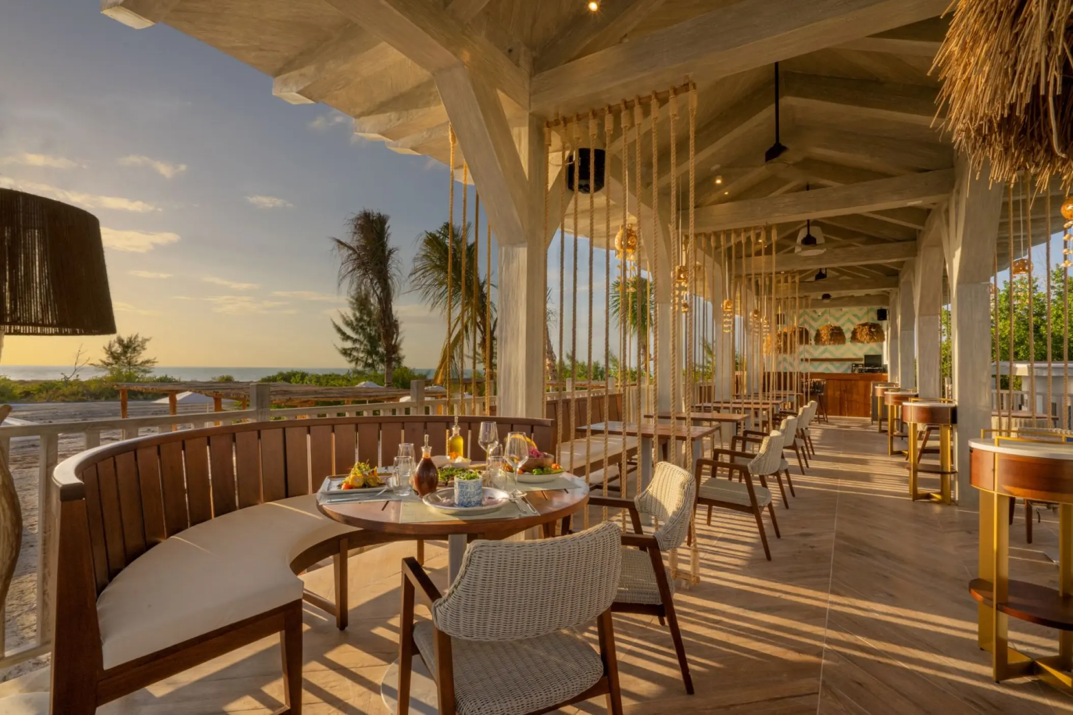 Open-air restaurant with wooden seating overlooking the beach at St. Somewhere Resort, Isla Holbox