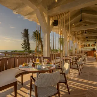 Open-air restaurant with wooden seating overlooking the beach at St. Somewhere Resort, Isla Holbox