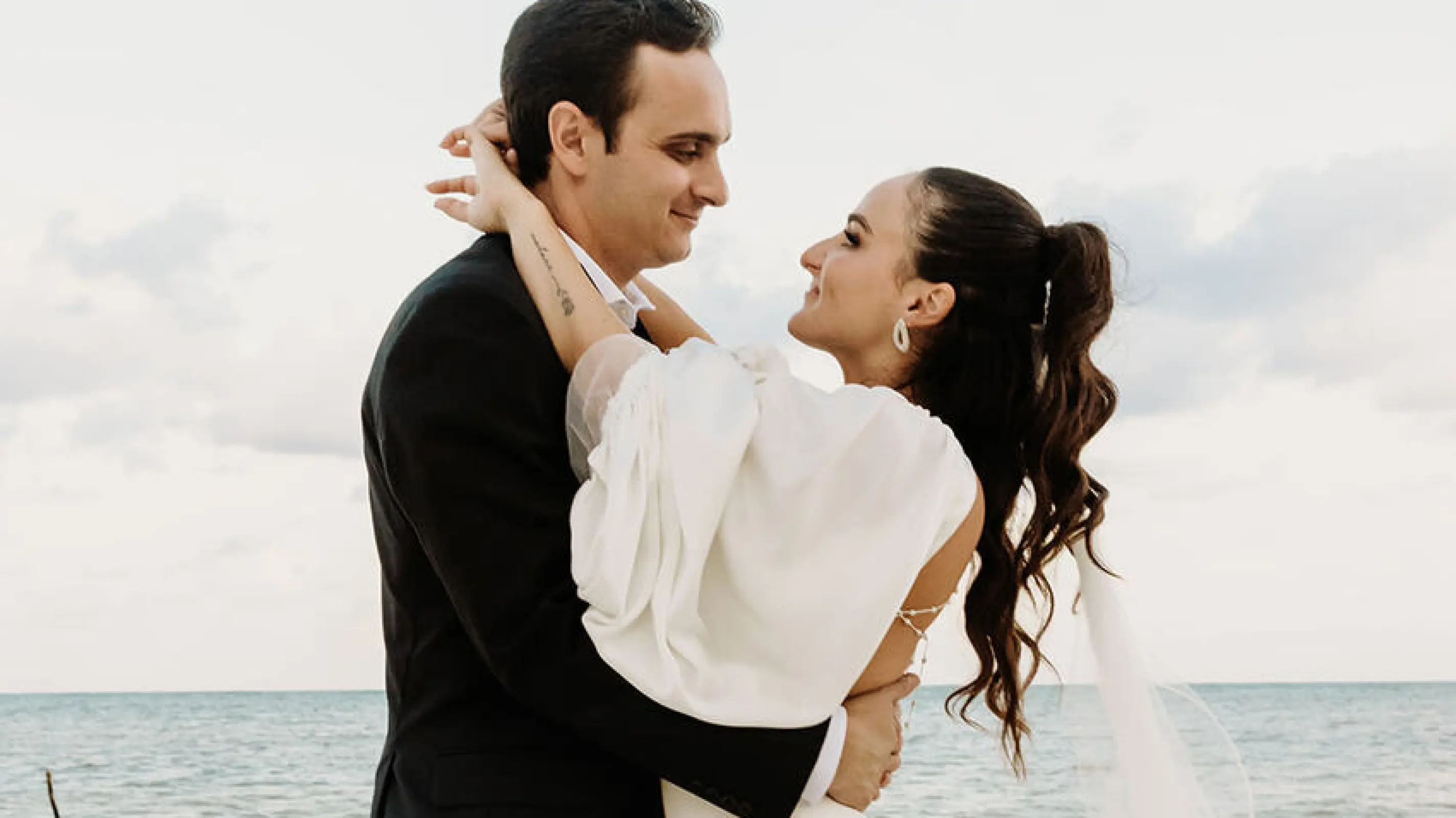 Alyssa & Ryan embracing during their beach wedding ceremony portrait