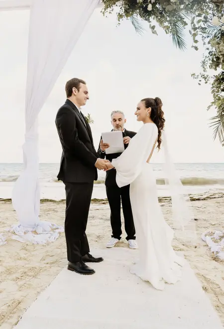 Alyssa and Ryan holding hands during their beach ceremony at Dreams Natura, Riviera Maya