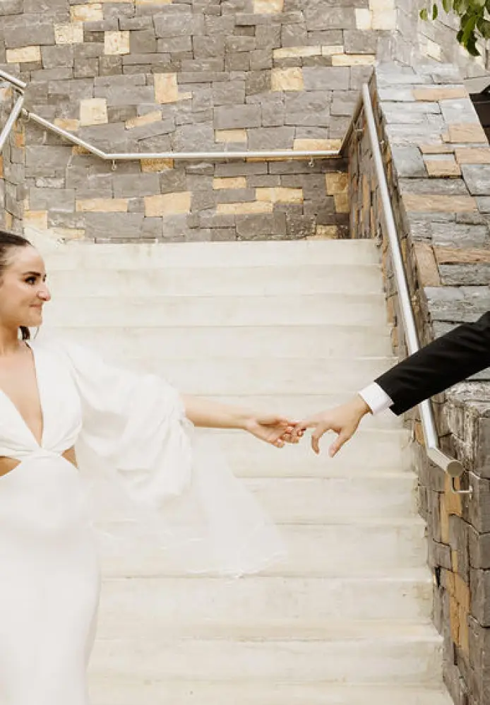 Alyssa & Ryan holding hands on a stone staircase at Dreams Natura, Riviera Maya
