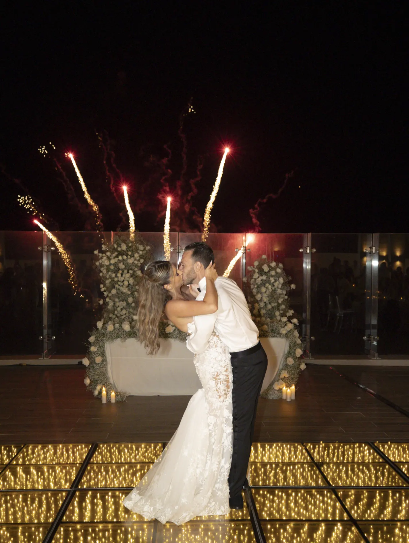 Andreana and Alessandro kiss on a light-up dance floor during wedding fireworks at Royalton Splash Riviera Cancun