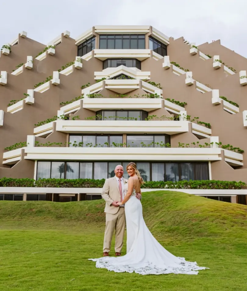 Anne & Mitch standing on the lawn in front of the pyramid building at Paradisus Cancun