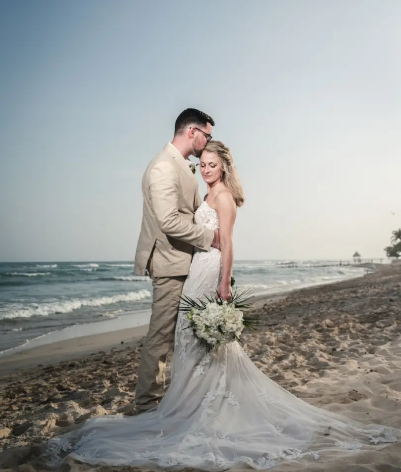 Danielle & Derrek's beach portrait with the groom kissing the bride's forehead