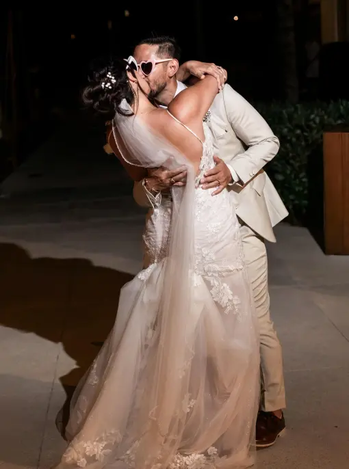 Danielle & Junya sharing a kiss while wearing sunglasses at their reception