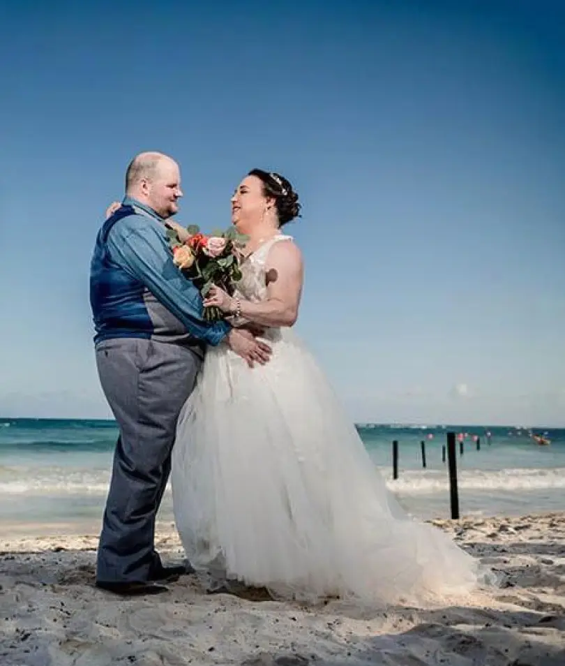 Erica & Alex smiling at each other during their beach wedding