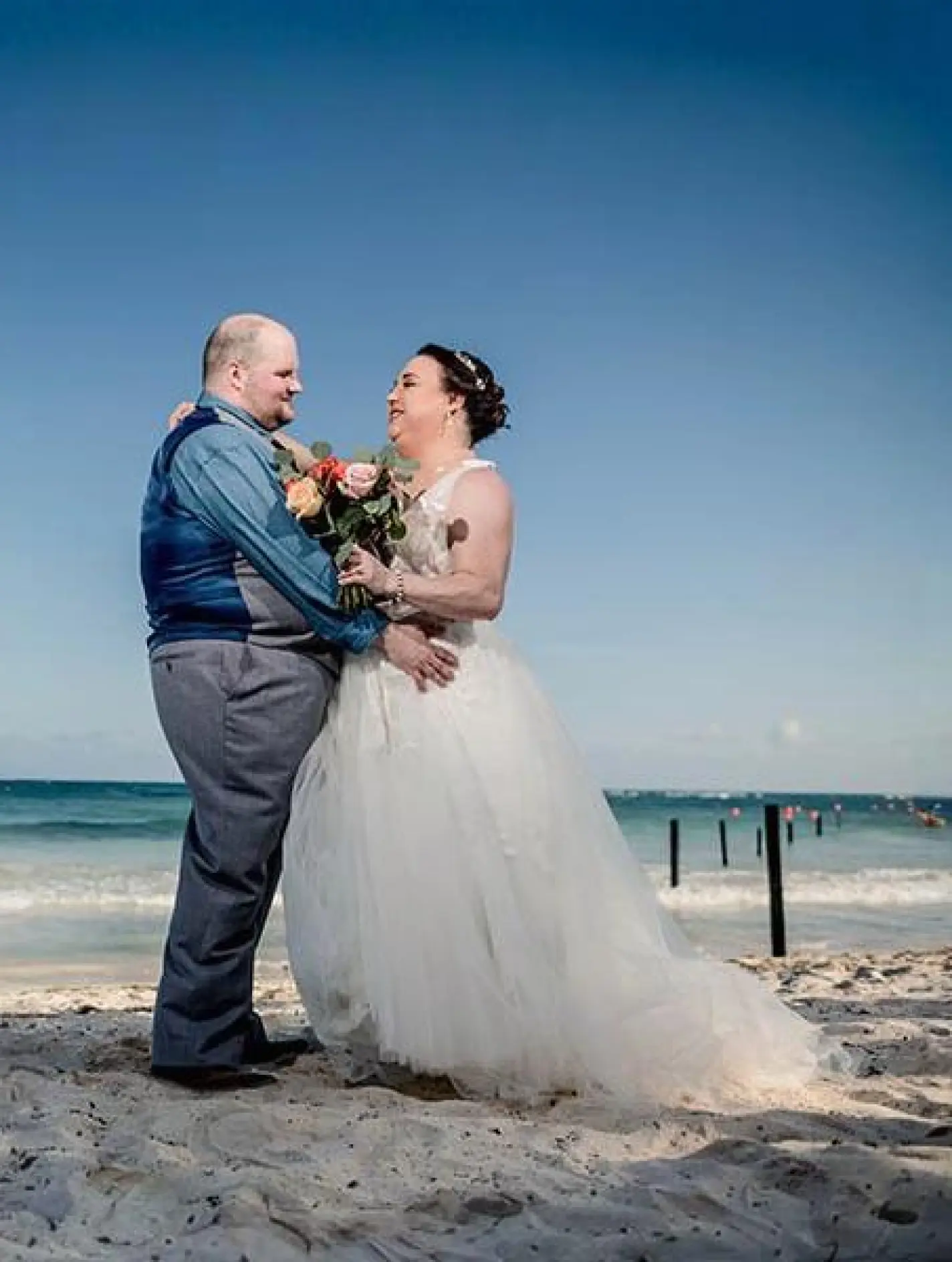 Erica & Alex smiling at each other during their beach wedding