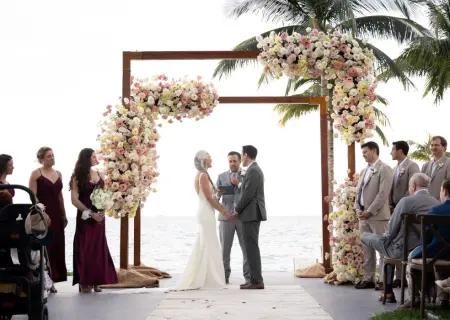 Lindsey & Jeff's beachfront wedding ceremony under a floral arch at Garza Blanca Cancun