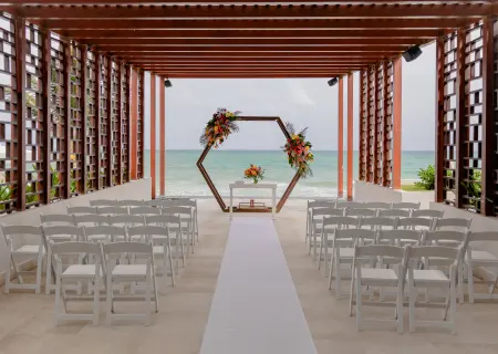 Hexagonal floral arch and white chairs at a pergola wedding ceremony, Dreams Jade, Riviera Maya