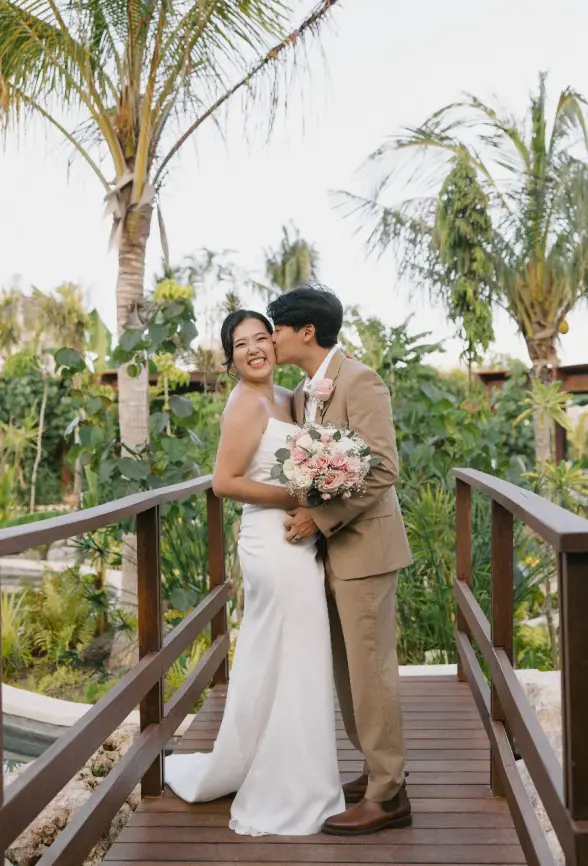 Sophie & Joonmo posing on a wooden bridge at Secrets Playa Blanca, Cancun