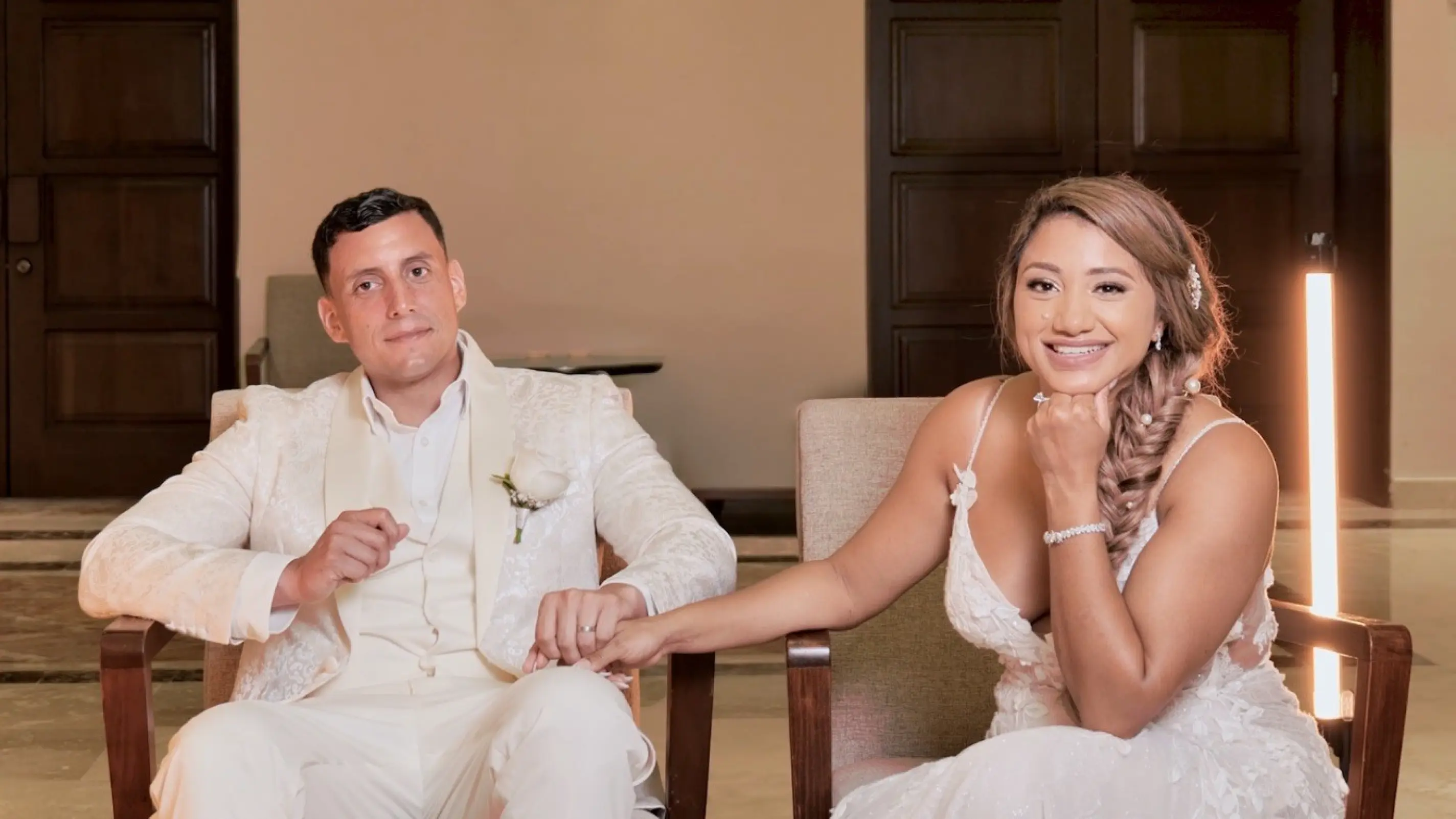 Keilan & Vince sitting together and holding hands during their wedding celebration