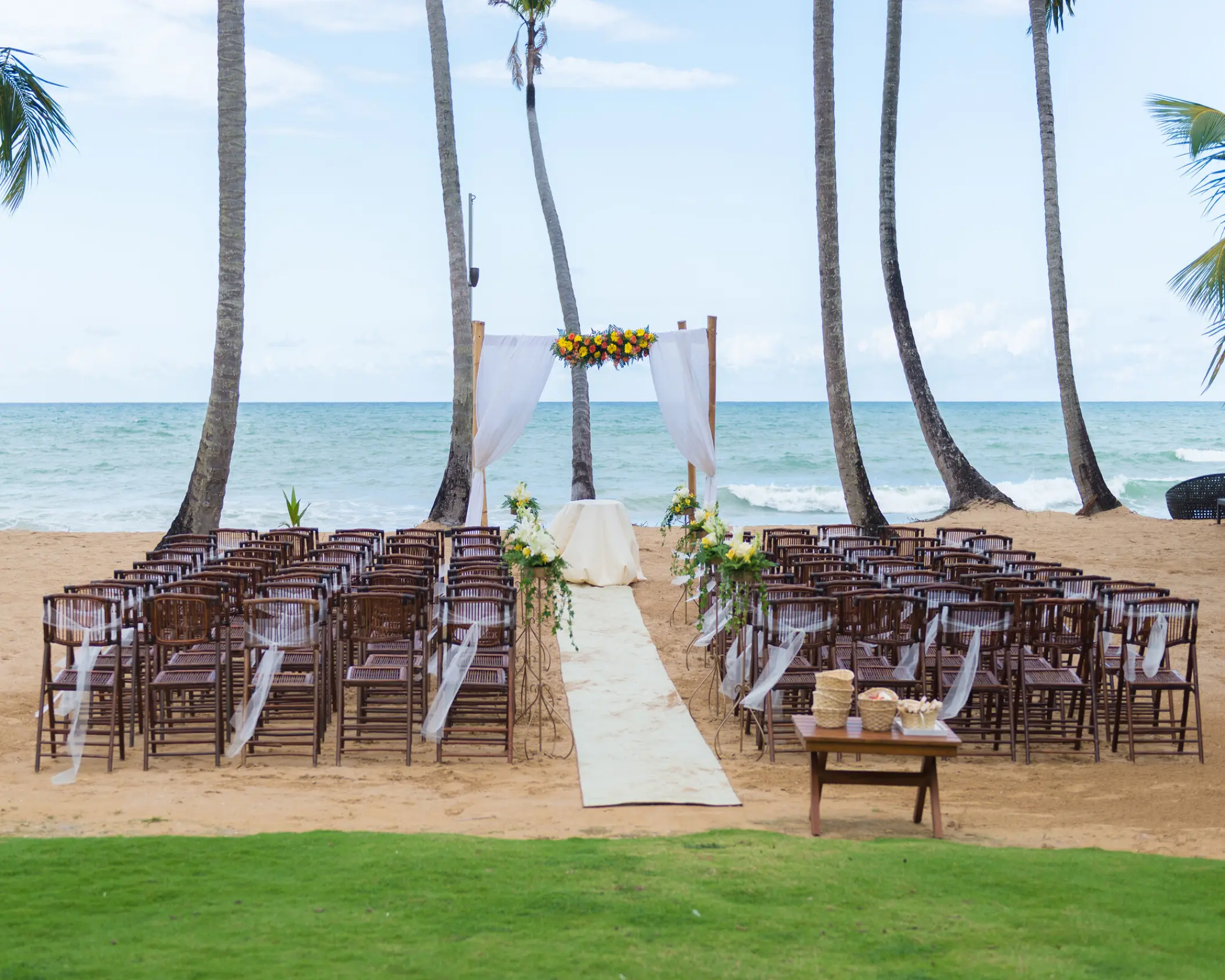 Beachfront wedding ceremony setup with wooden chairs and white arch at Sublime Samana, Samana