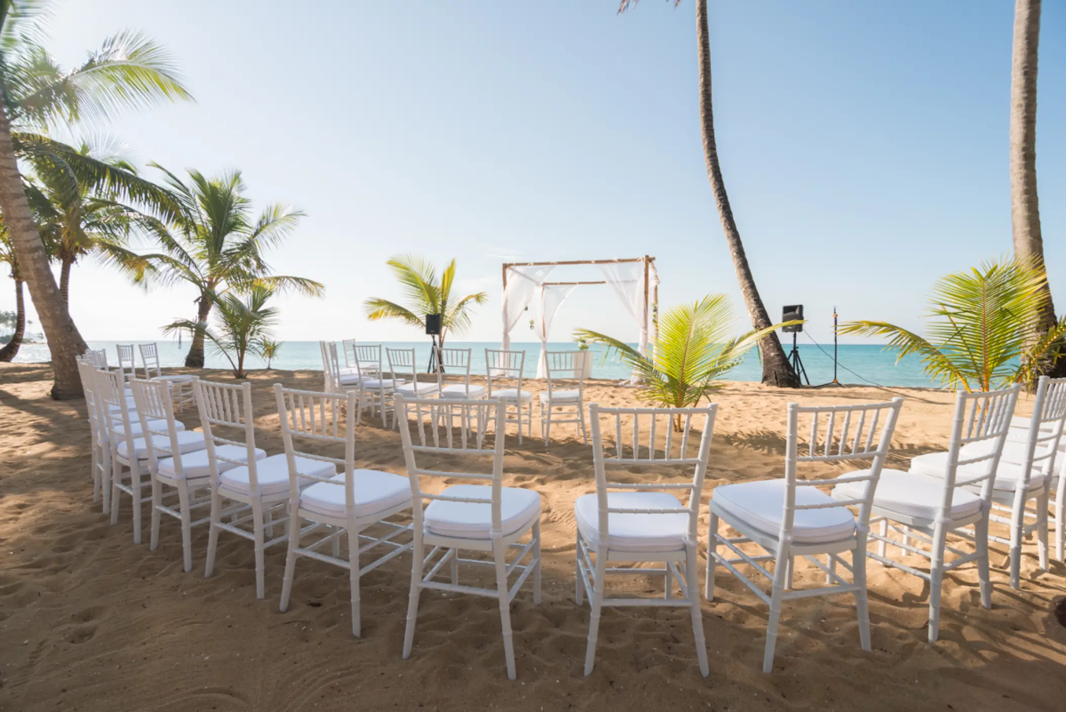 Beachfront wedding ceremony with white chairs and a wooden canopy at Sublime Samaná, Samana