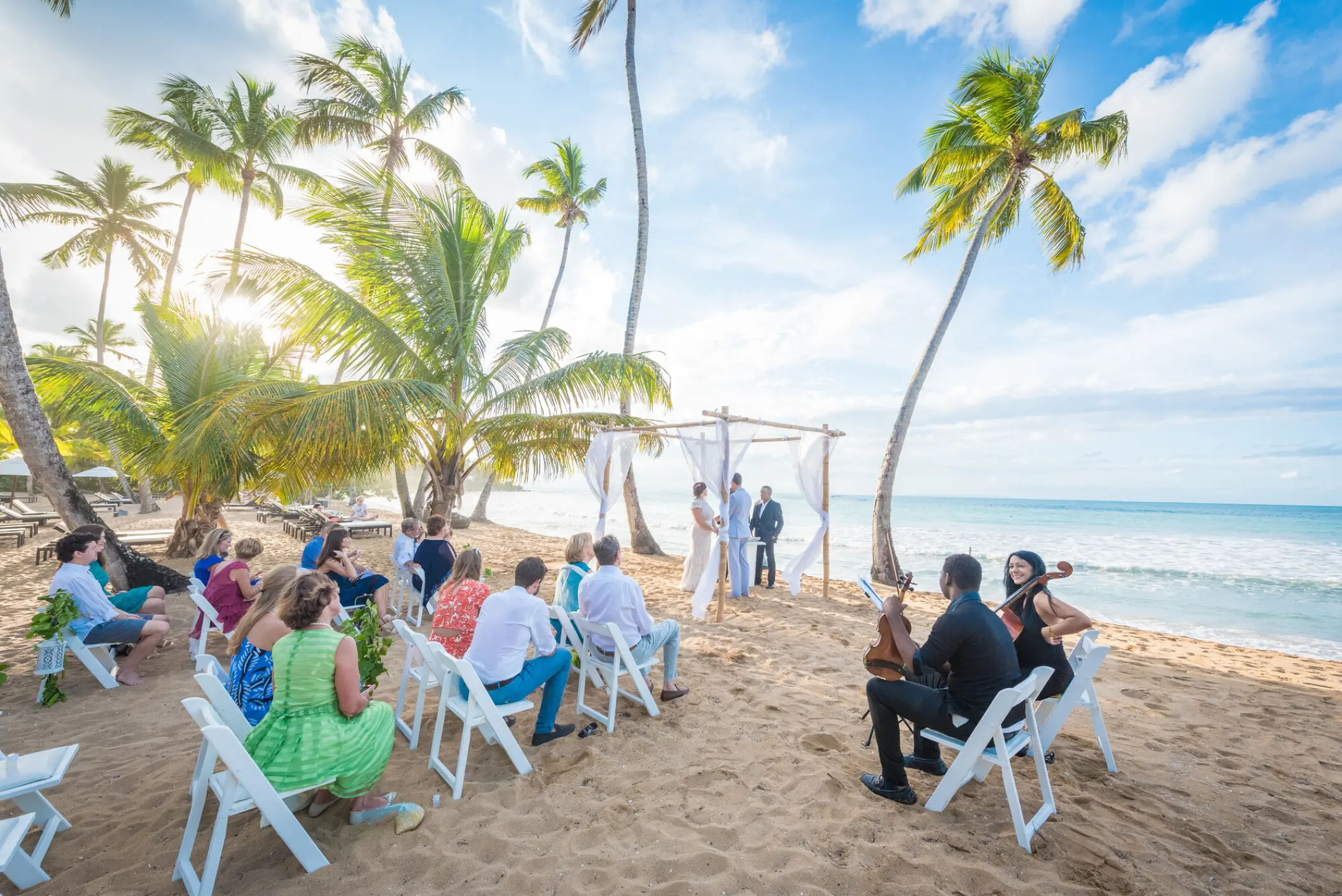 Beachfront wedding ceremony with white folding chairs and a bamboo arch at Sublime Samaná, Samana