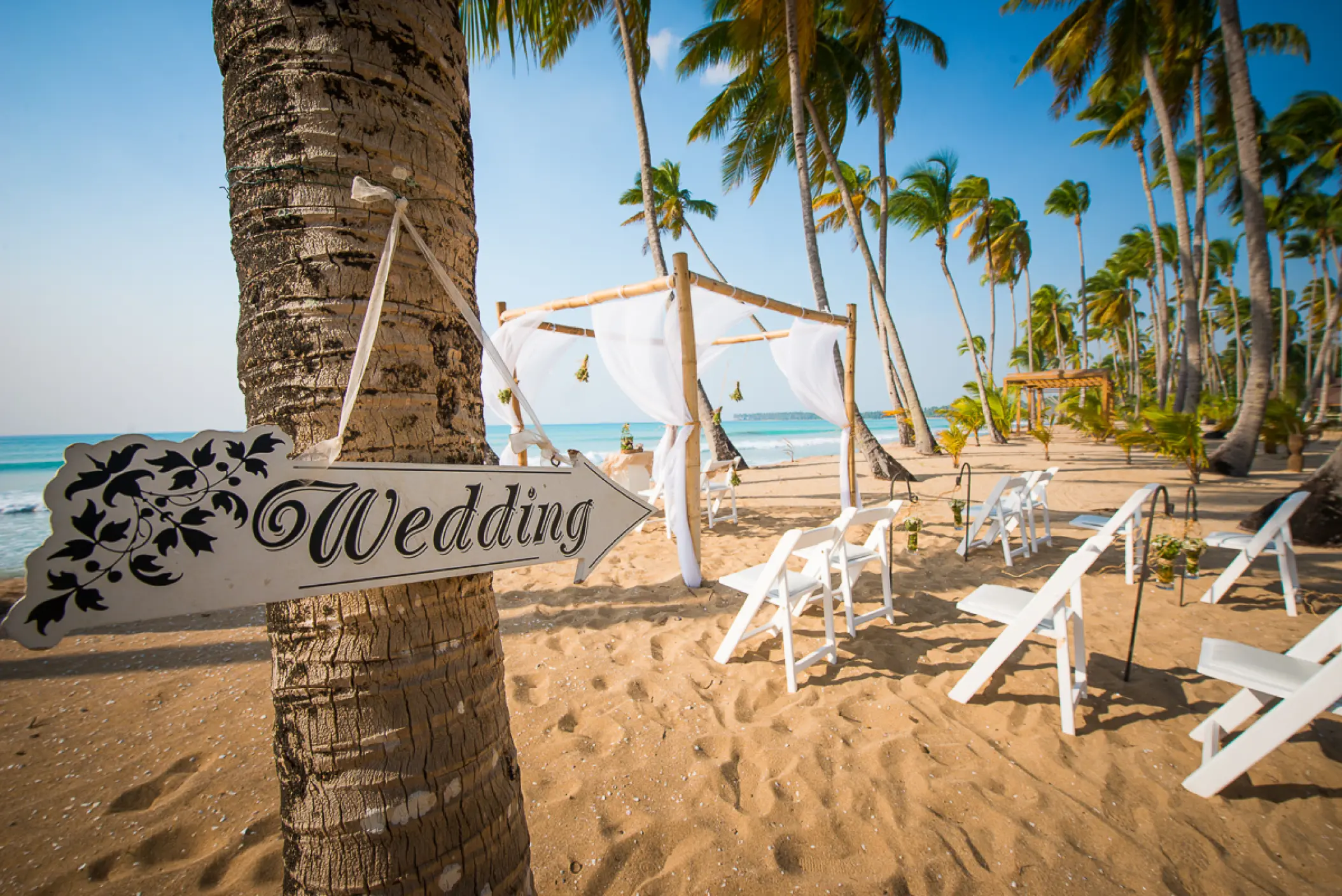 Beachfront wedding ceremony setup with white chairs and a bamboo huppah at Sublime Samaná, Samana