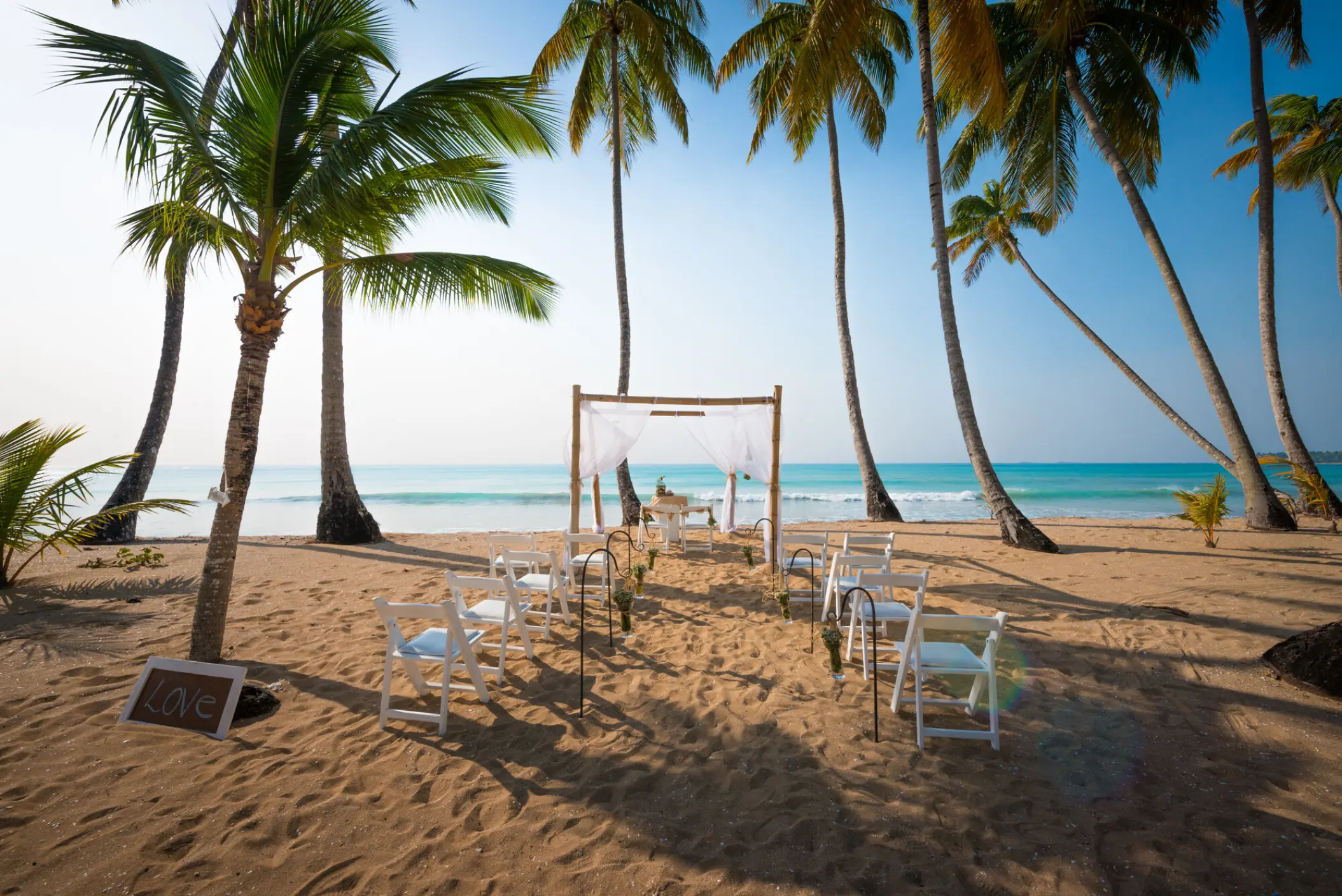 Beachfront wedding ceremony with white chairs and fabric gazebo at Sublime Samaná, Samana