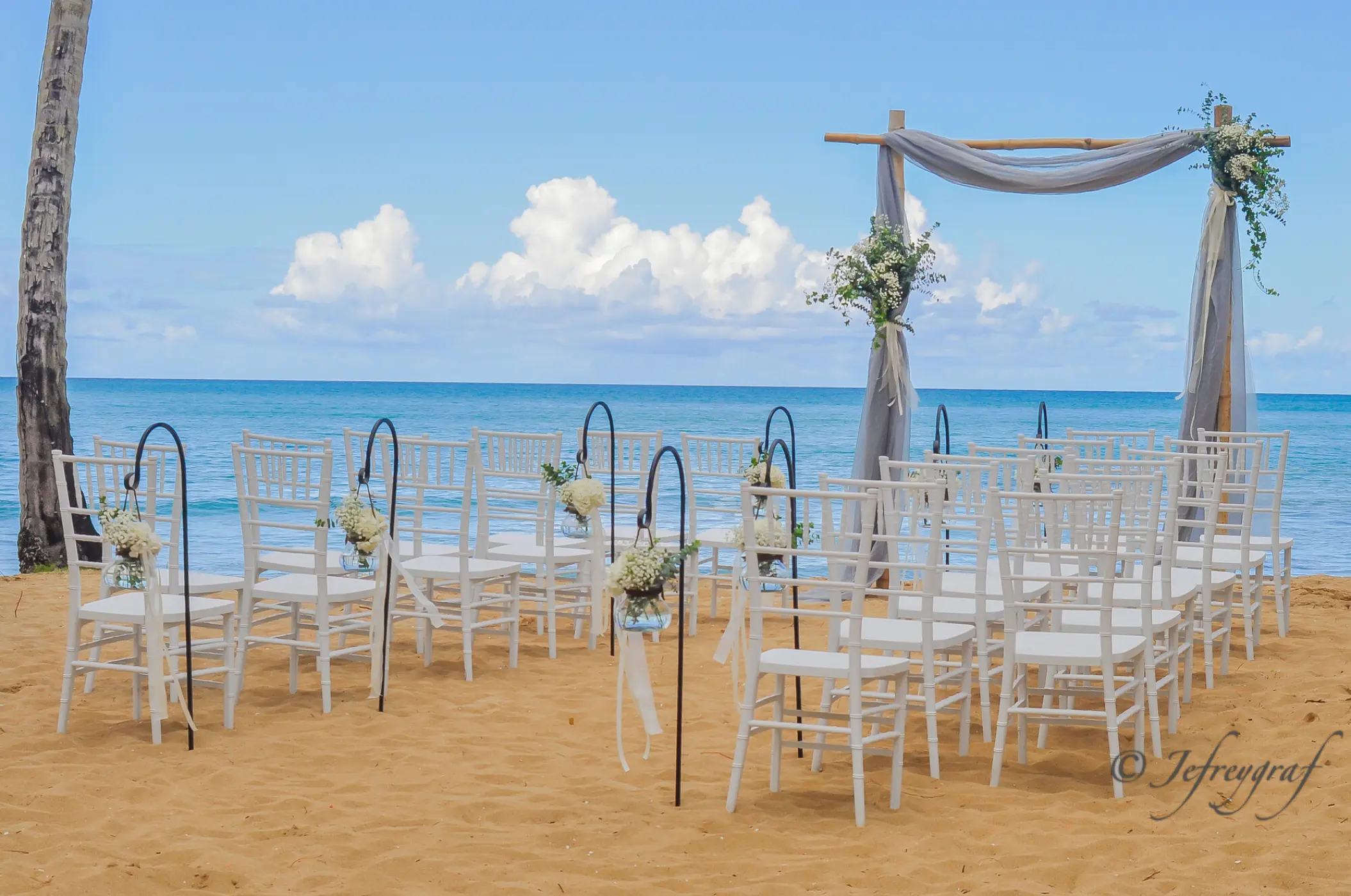Beachfront wedding ceremony with white chairs and floral arch at Sublime Samana, Samana