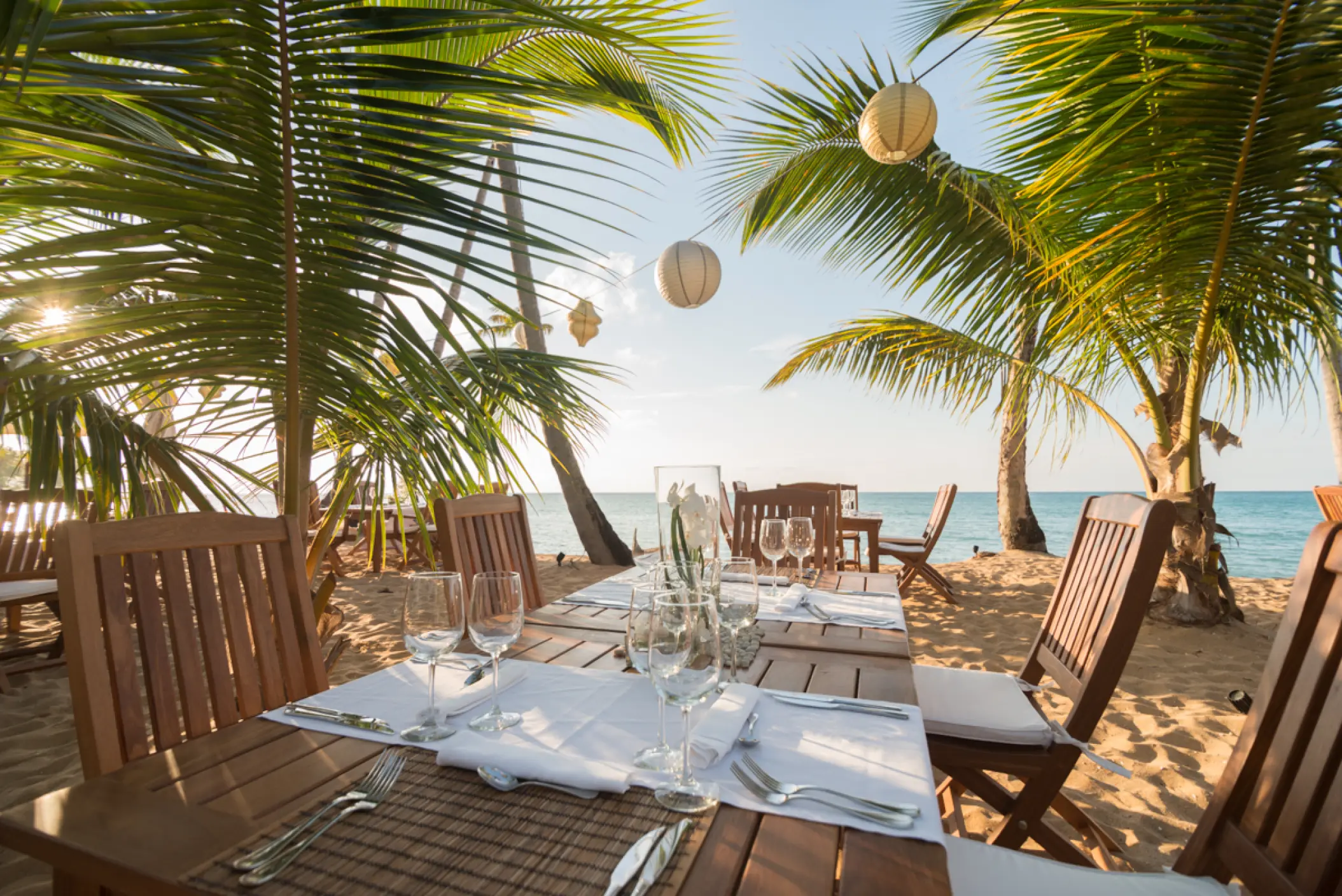 Beachfront wedding reception tables under palm trees at Sublime Samana, Samana